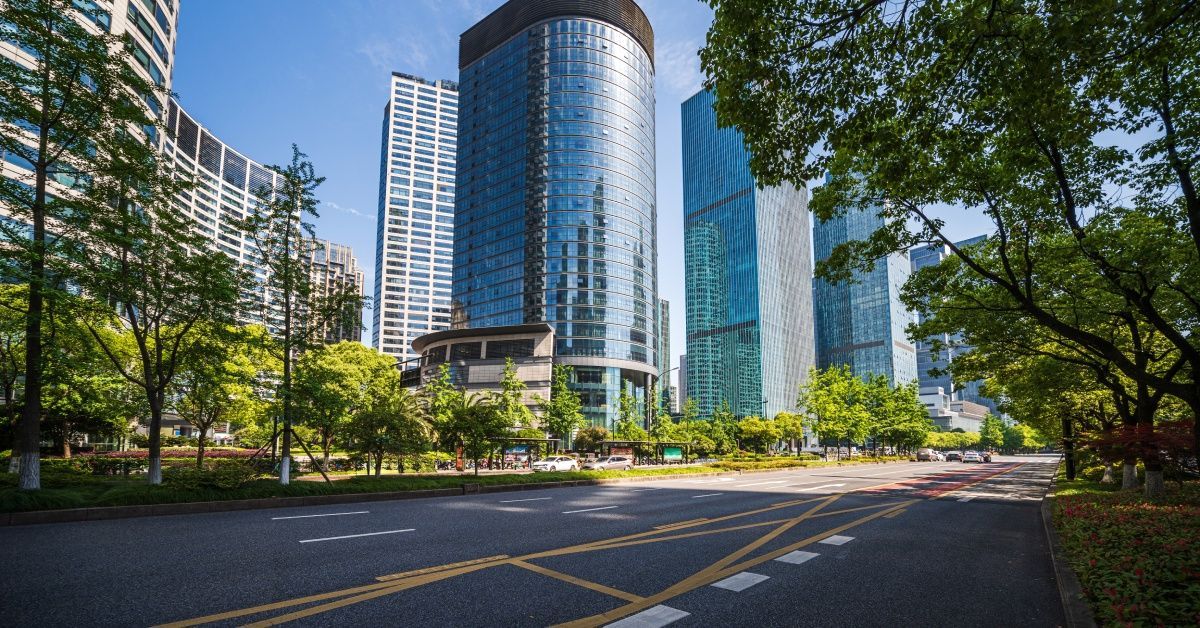 An urban landscape features skyscrapers alongside lush greenery that stretches across the area.