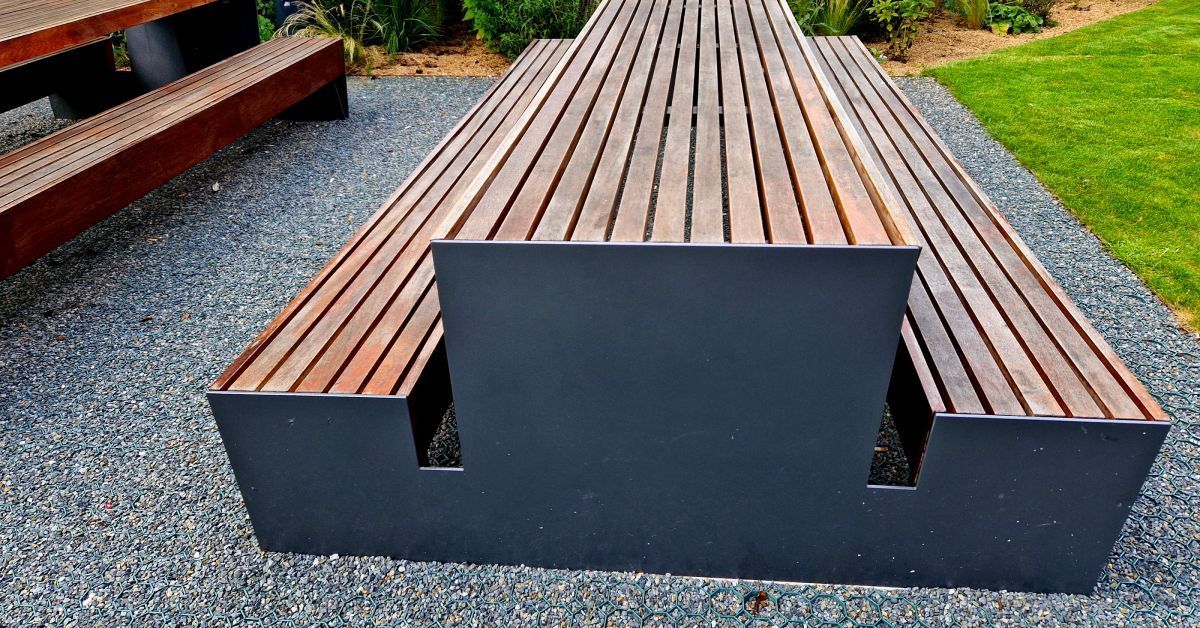 A modern picnic bench in a city park established atop a patch of land covered with permeable paving.