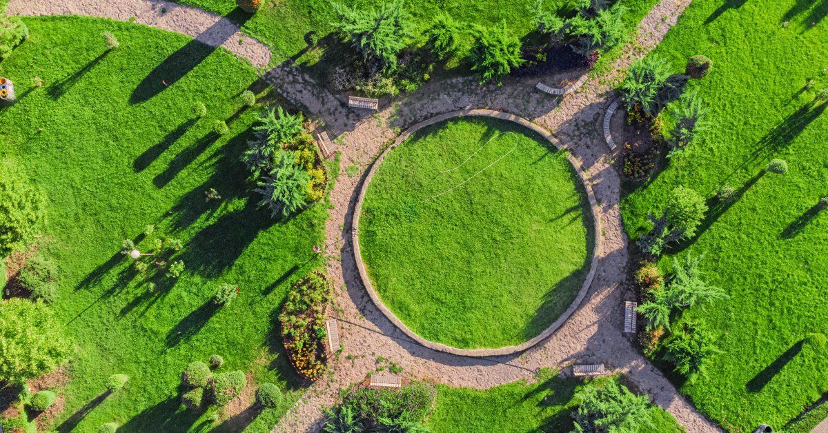 A garden and park area with trees, bushes, and a circular path winding around it from a bird's-eye view.