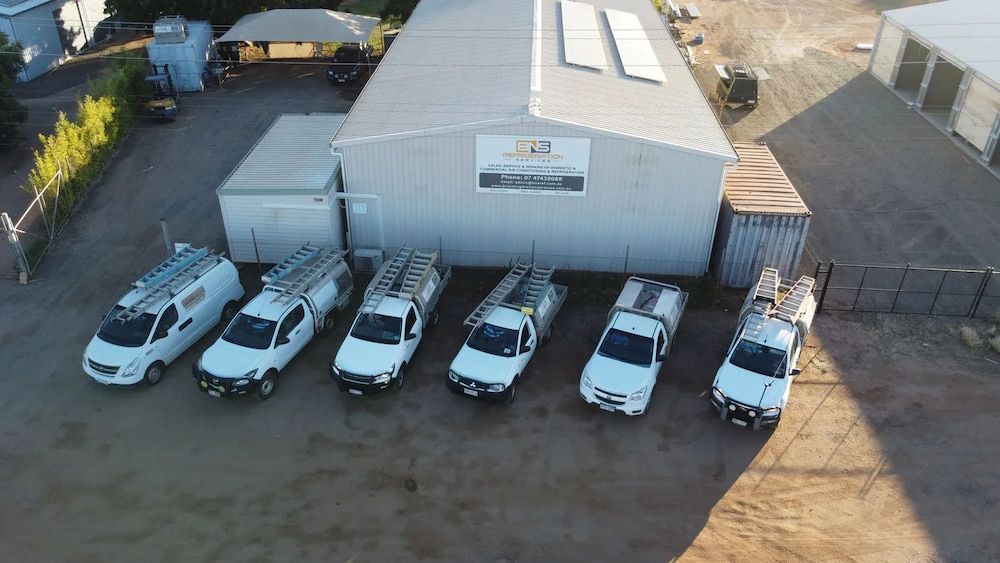 Fleet of White Work Vans Parked in Front of a Metal Building — BNS Refrigeration Services in Healy, QLD