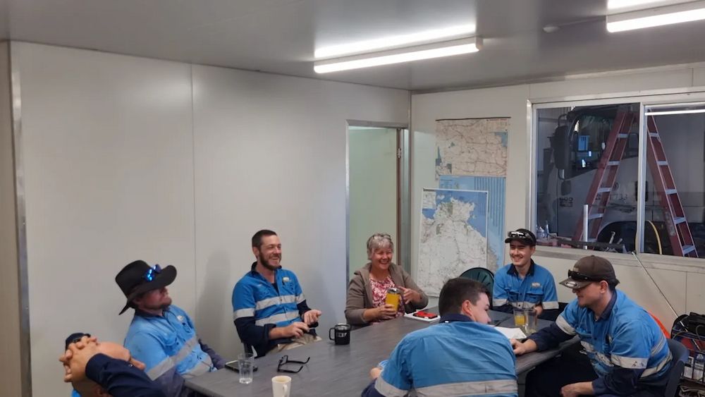 Group of Workers in Blue Shirts Seated Around a Table — BNS Refrigeration Services in Healy, QLD