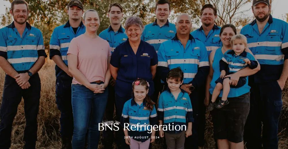 Team of BNS Refrigeration employees outdoors, some with children, wearing work uniforms.— BNS Refrigeration Services in Healy, QLD
