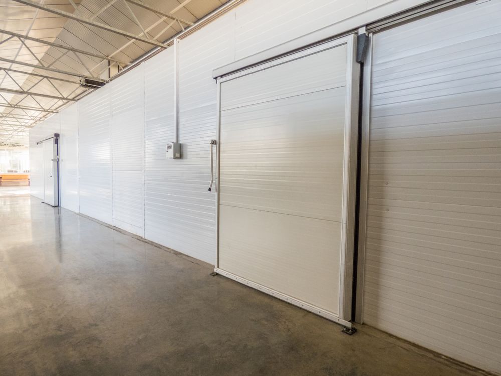 White Sliding Industrial Door in a Warehouse — BNS Refrigeration Services in Healy, QLD