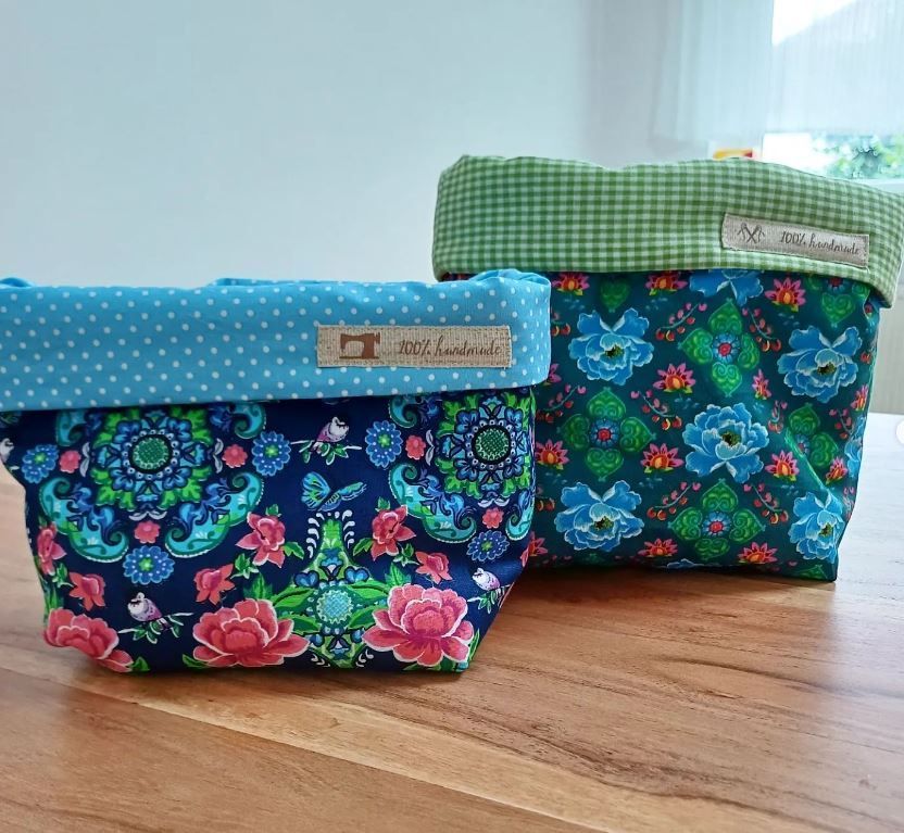 zwei Kisten mit Blumenmustern sitzen auf einem Holztisch .