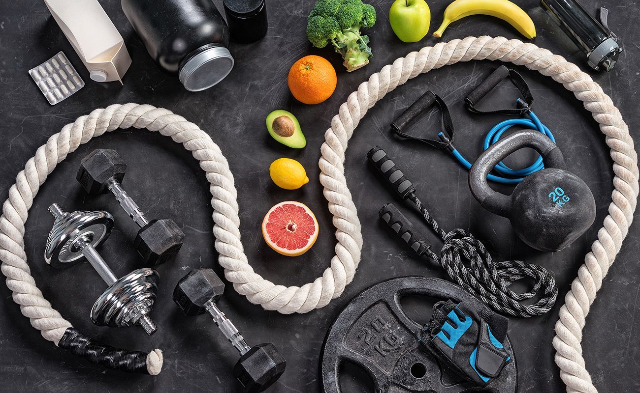 A bunch of ropes , dumbbells , fruits and vegetables on a table.