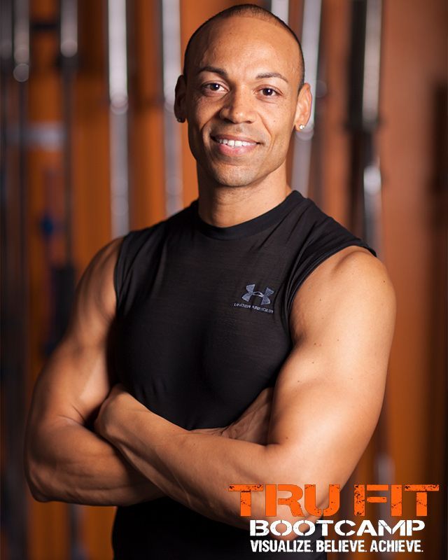 A man with his arms crossed is wearing a black under armour tank top