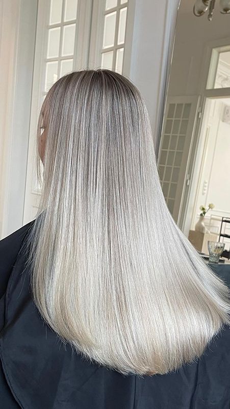A Woman With Long Blonde Hair Is Sitting In Front Of A Mirror — Sophisticut Hair Salon in Mysterton, QLD