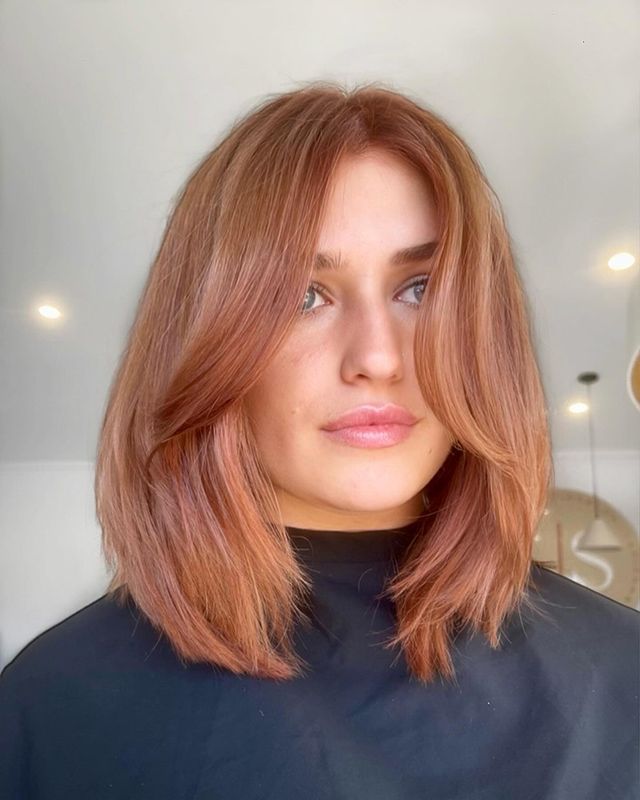 A Woman With Red Hair And A Black Shirt Is Standing In A Room — Sophisticut Hair Salon in Mysterton, QLD