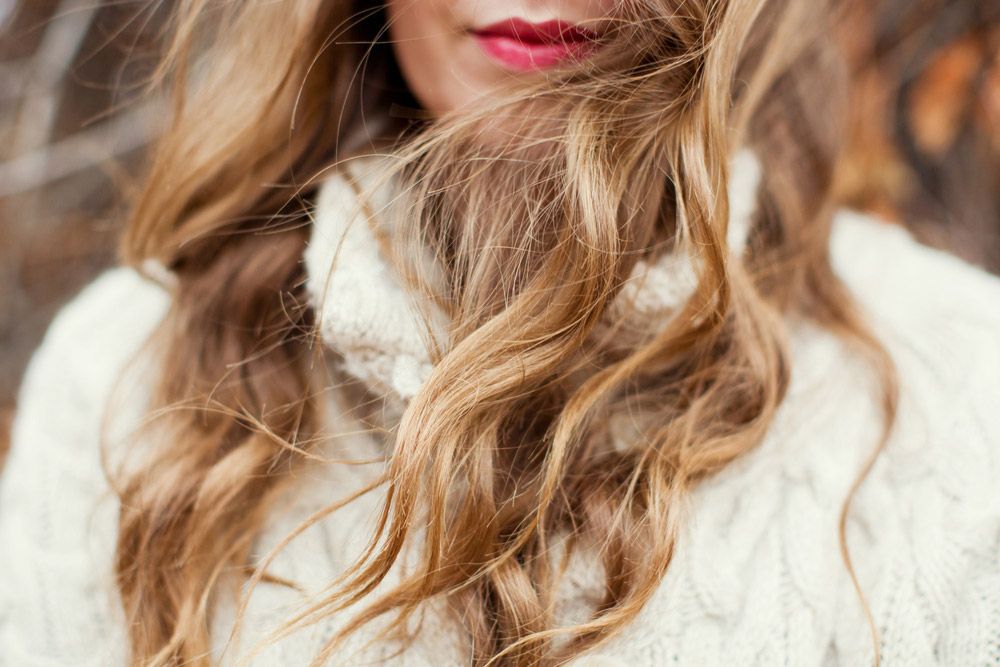 A Woman in a White Sweater With Her Hair Blowing in the Wind — Sophisticut Hair Salon in Mysterton, QLD