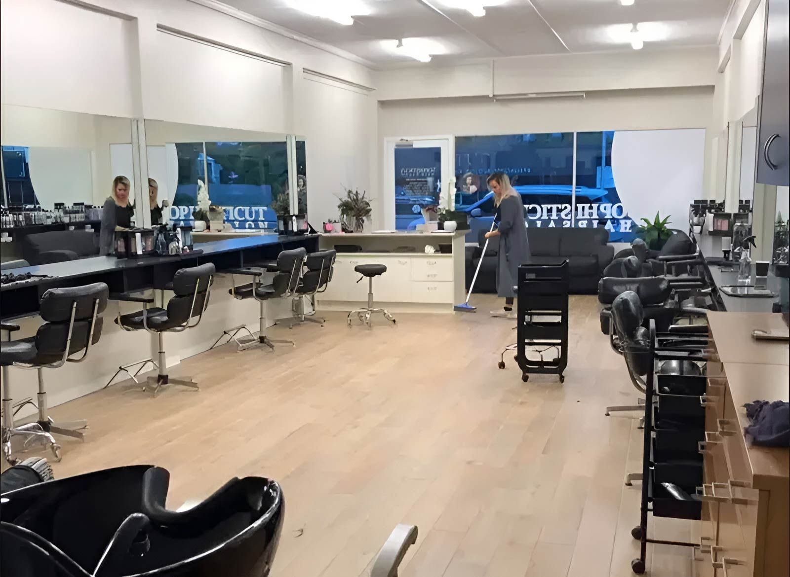 A Woman Is Cleaning Inside A Hair Salon With A Mop — Sophisticut Hair Salon in Mysterton, QLD
