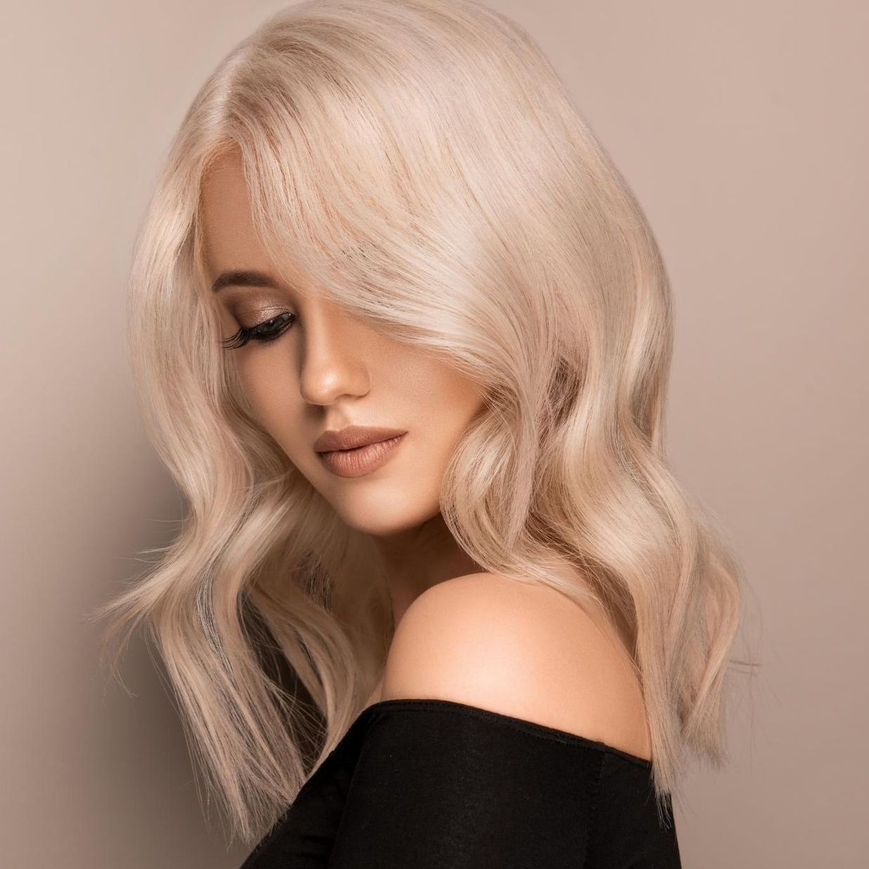 A Woman With Blonde Hair is Wearing a Black Top and Looking Down — Sophisticut Hair Salon in Mysterton, QLD