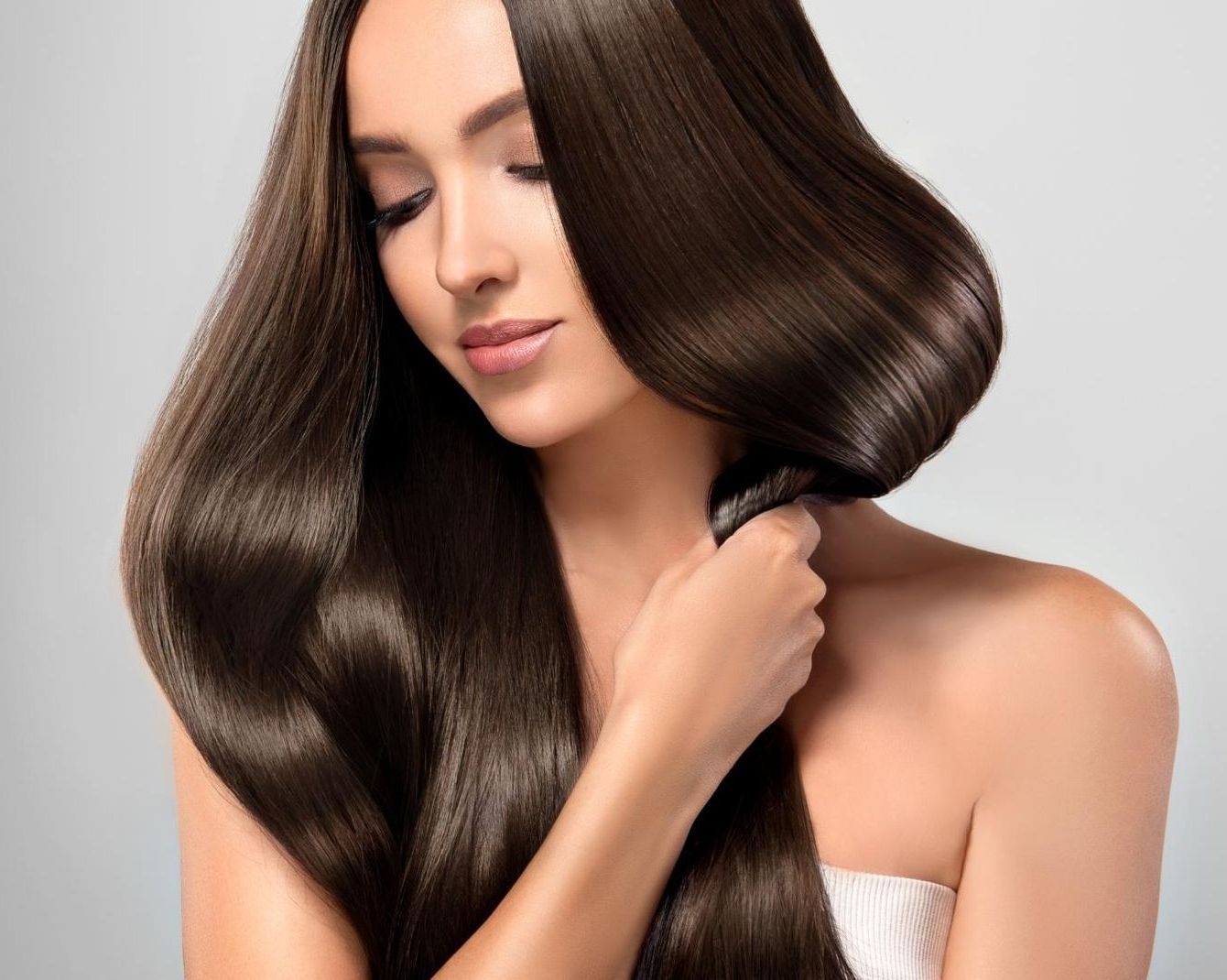 A Woman With Long Hair is Brushing Her Hair With a Brush — Sophisticut Hair Salon in Mysterton, QLD
