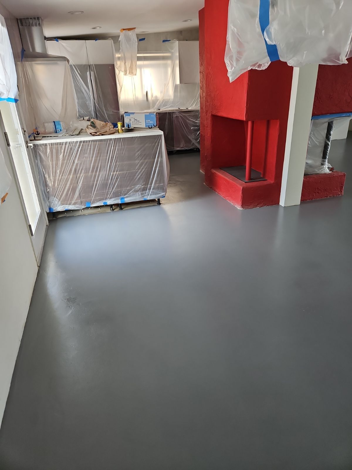 A living room with a gray floor and a red fireplace.
