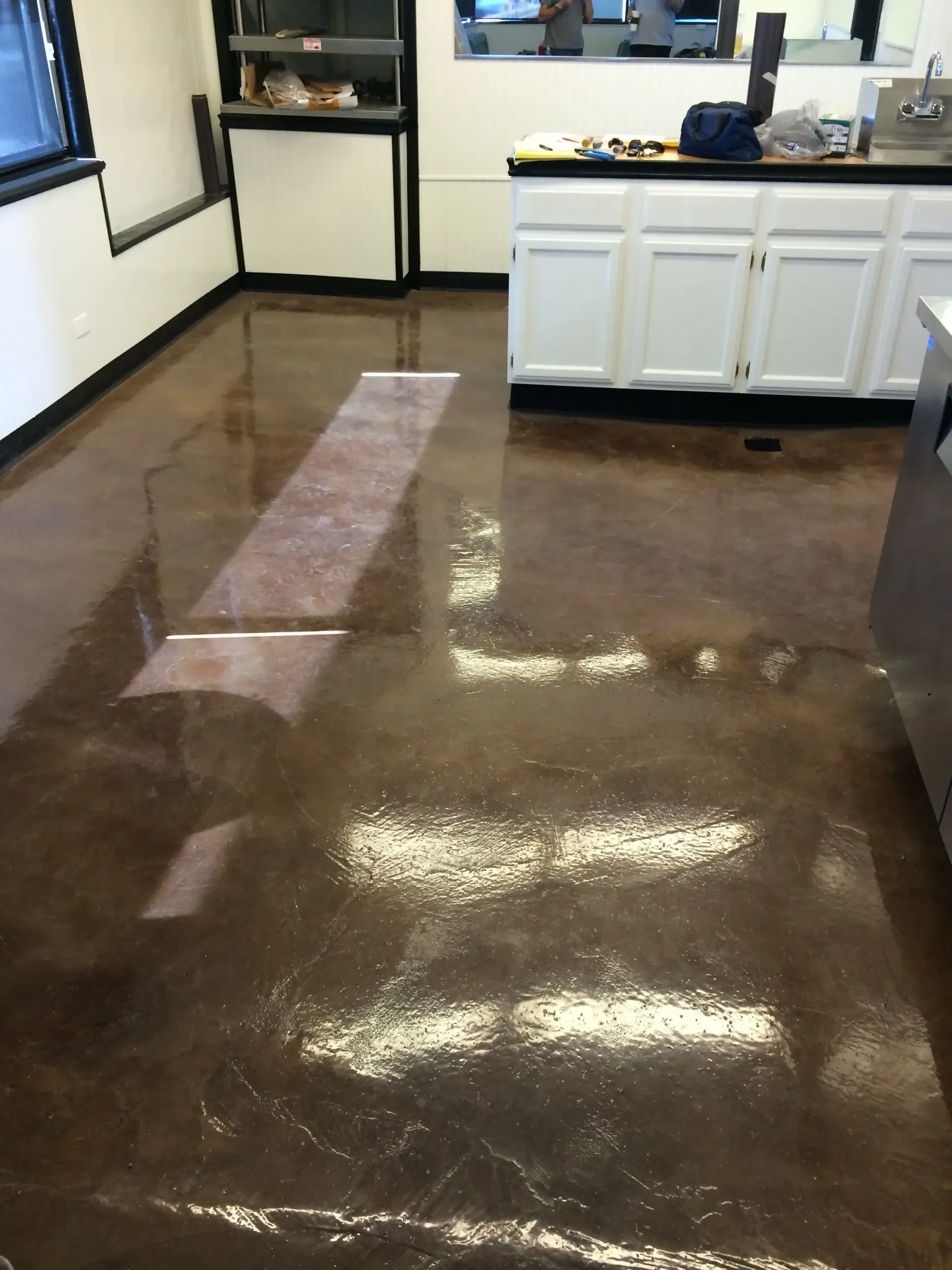 A kitchen with a brown floor and white cabinets