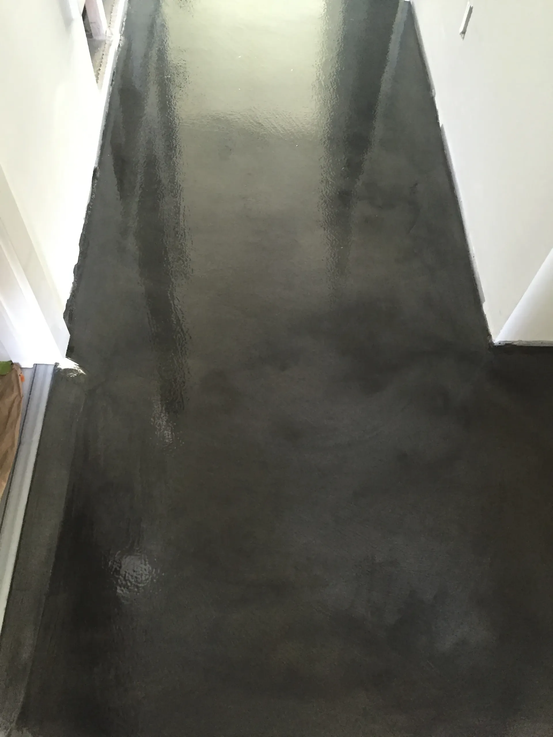 A hallway with a black concrete floor and white walls.