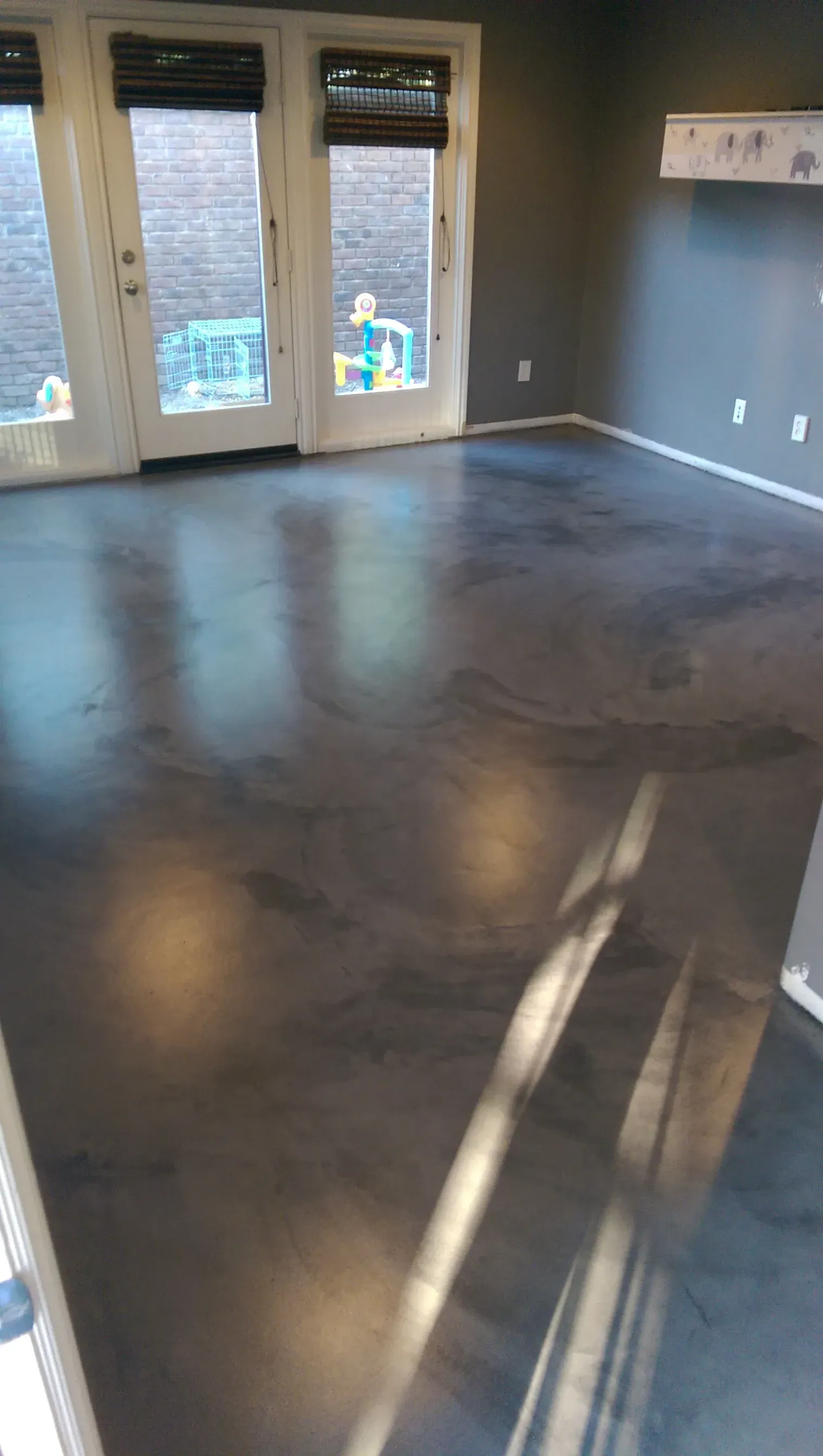 A living room with a black concrete floor and sliding glass doors.