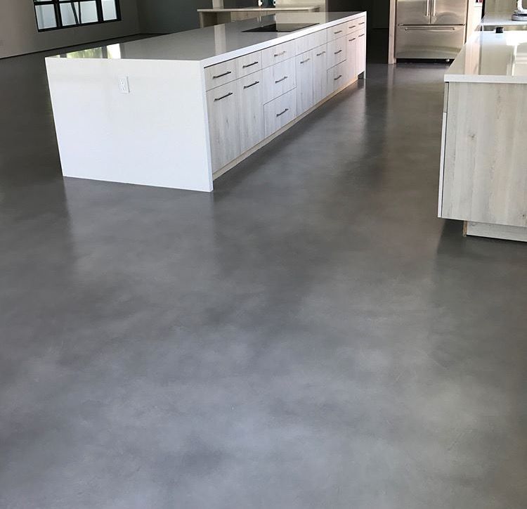 A kitchen with a concrete floor and white cabinets