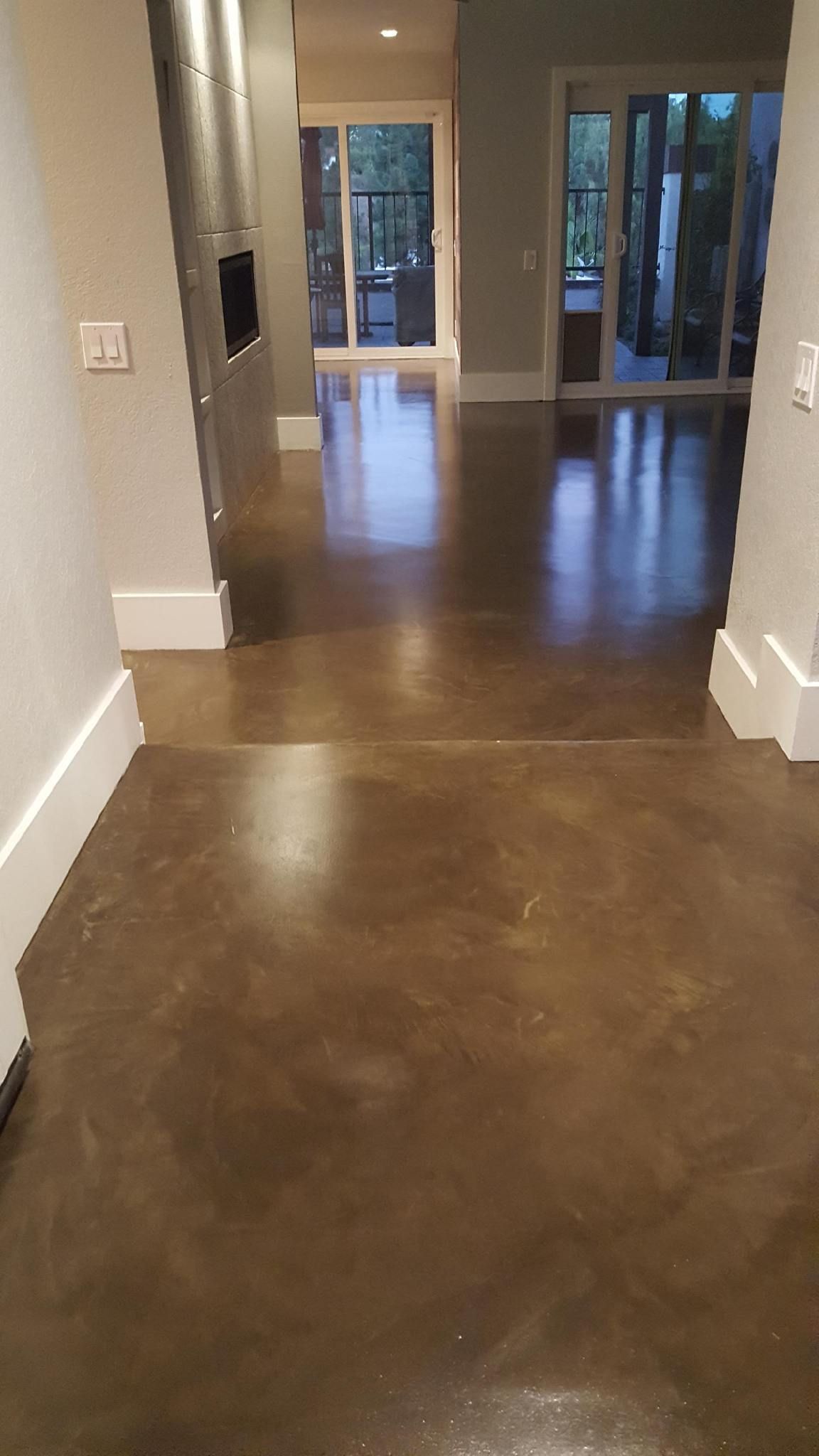 A hallway with a concrete floor and sliding glass doors leading to a living room.