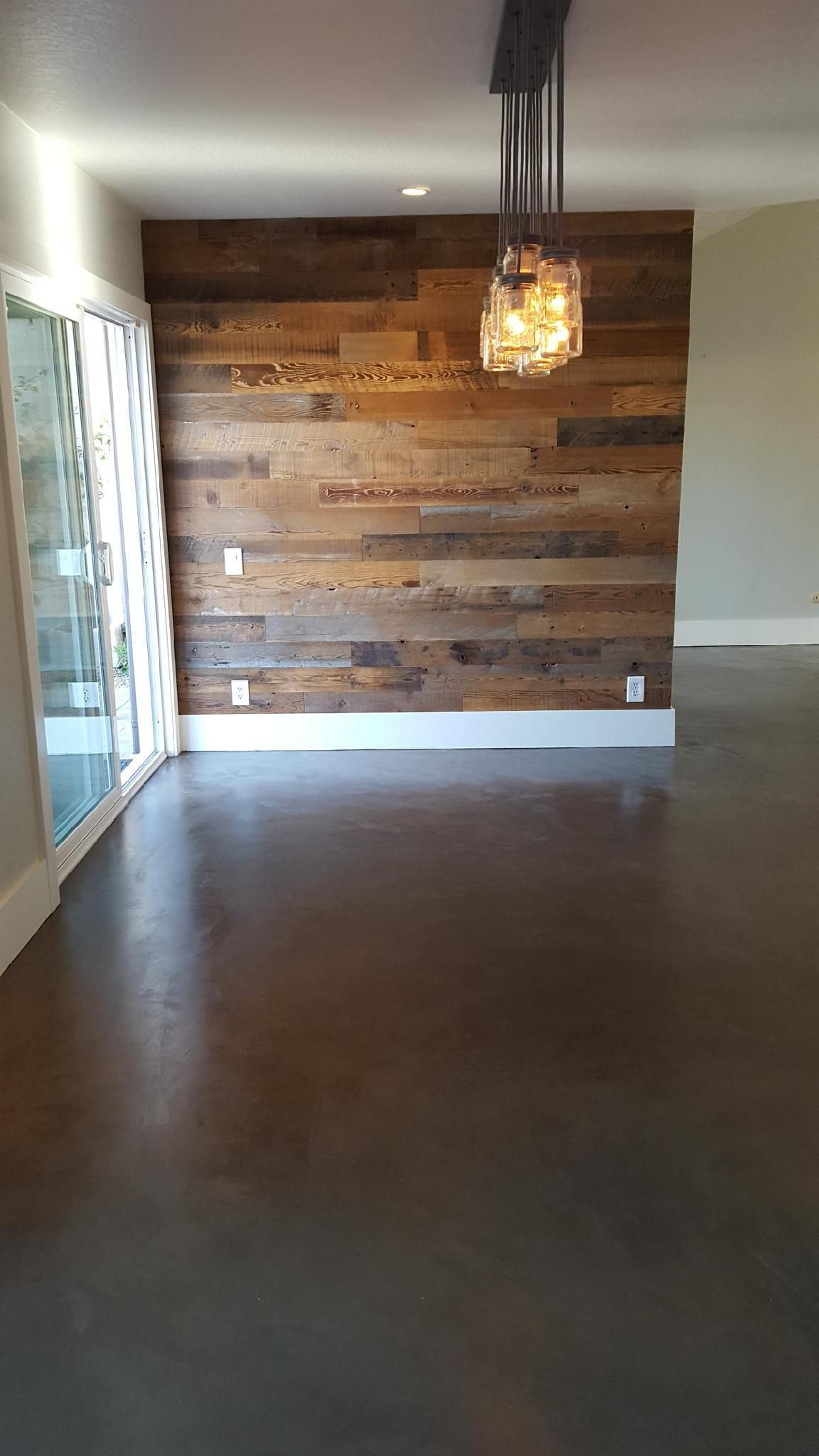An empty room with a wooden wall and a chandelier hanging from the ceiling.