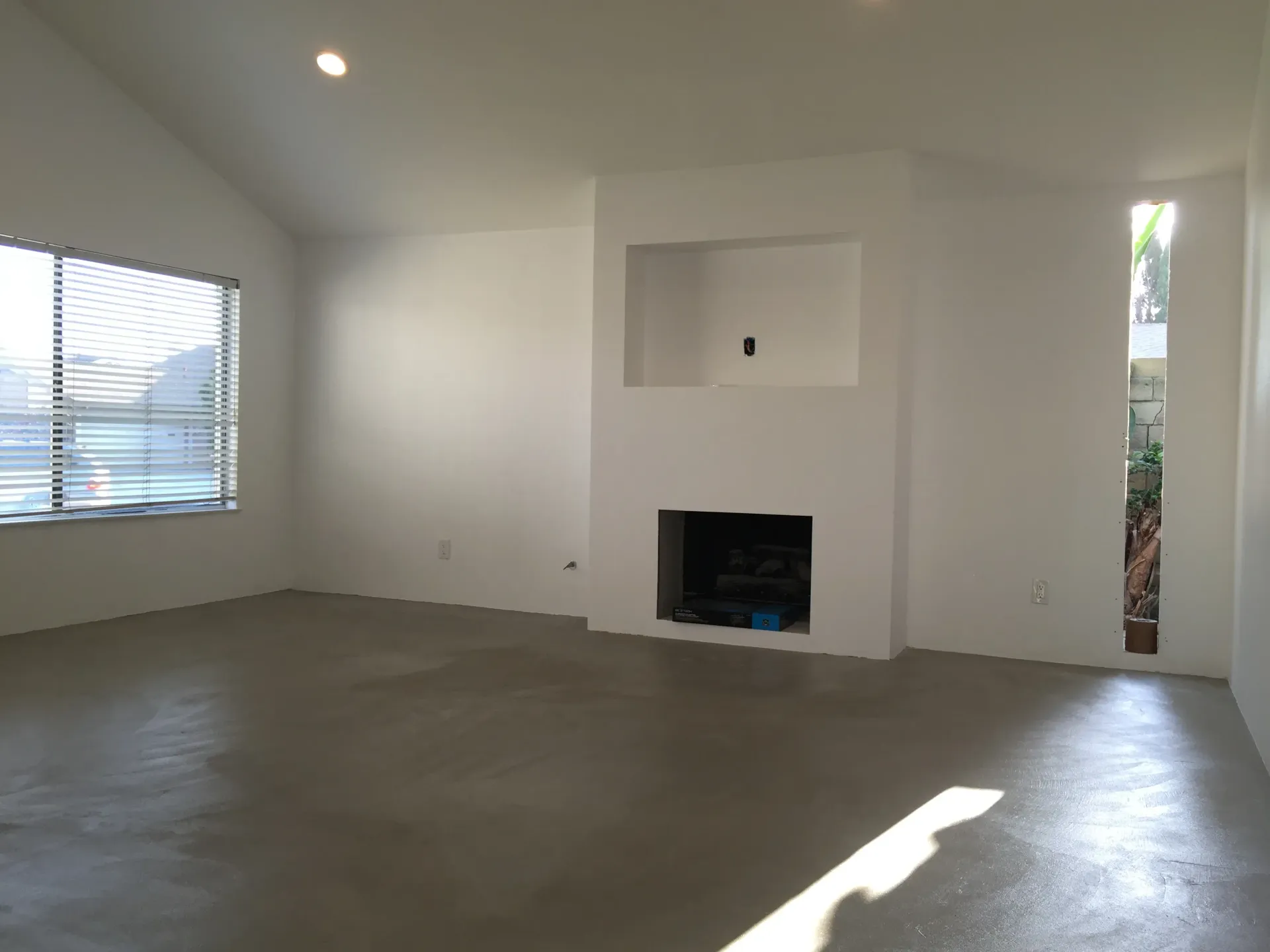 An empty living room with a fireplace and a window