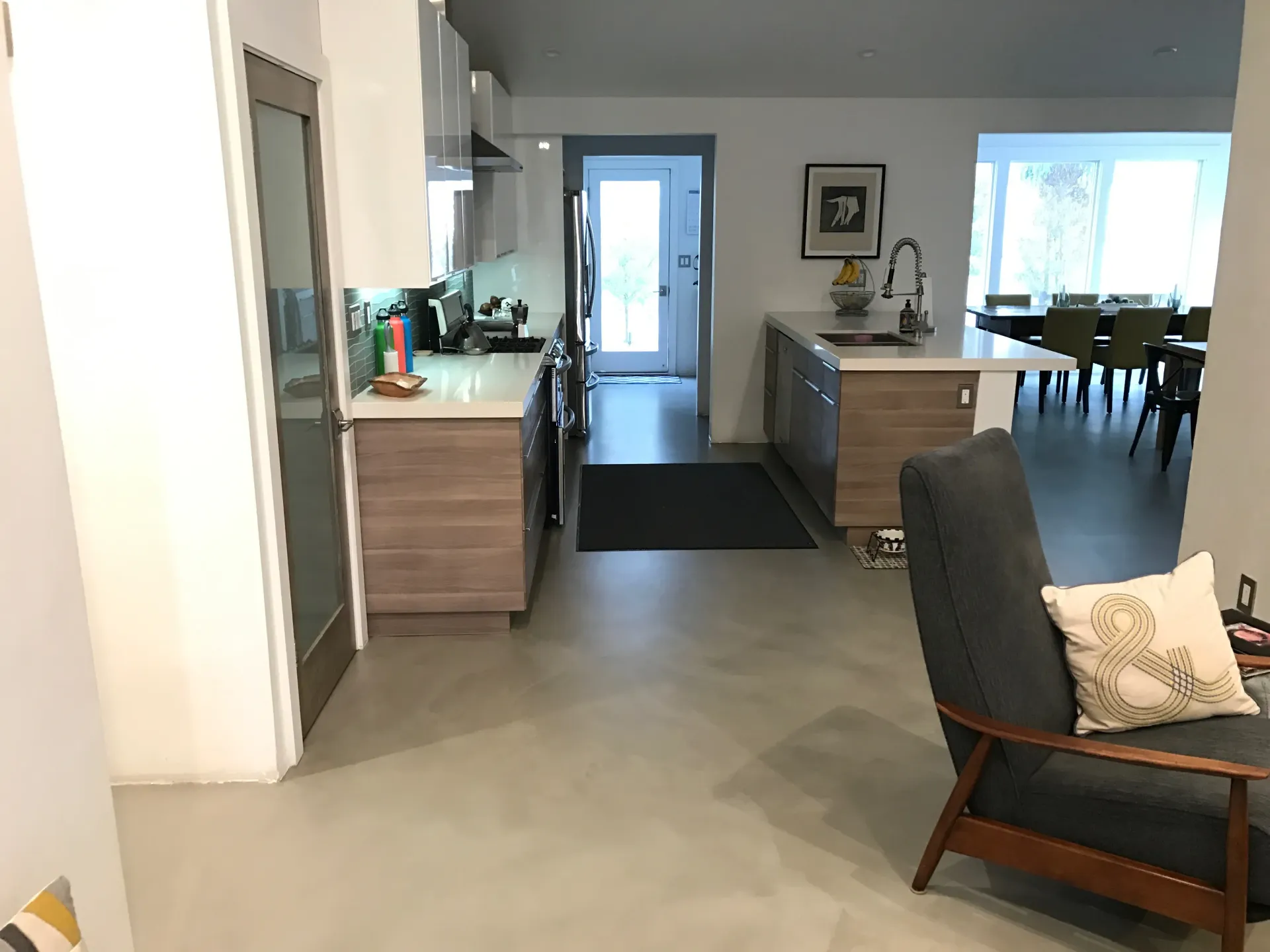 A living room with a chair and a kitchen in the background