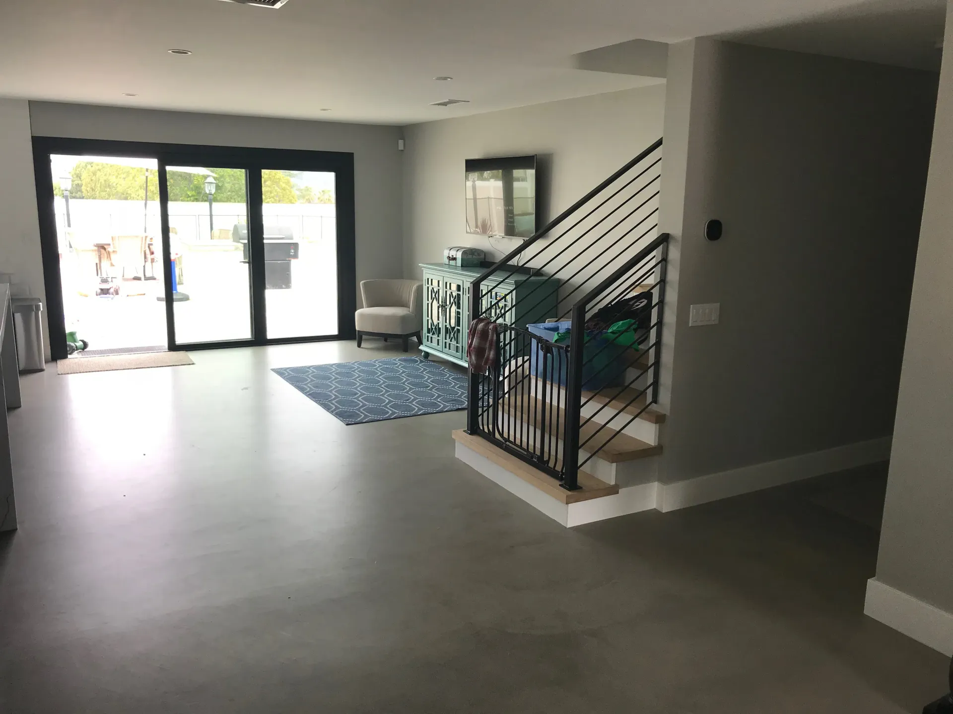 A living room with a staircase and sliding glass doors.