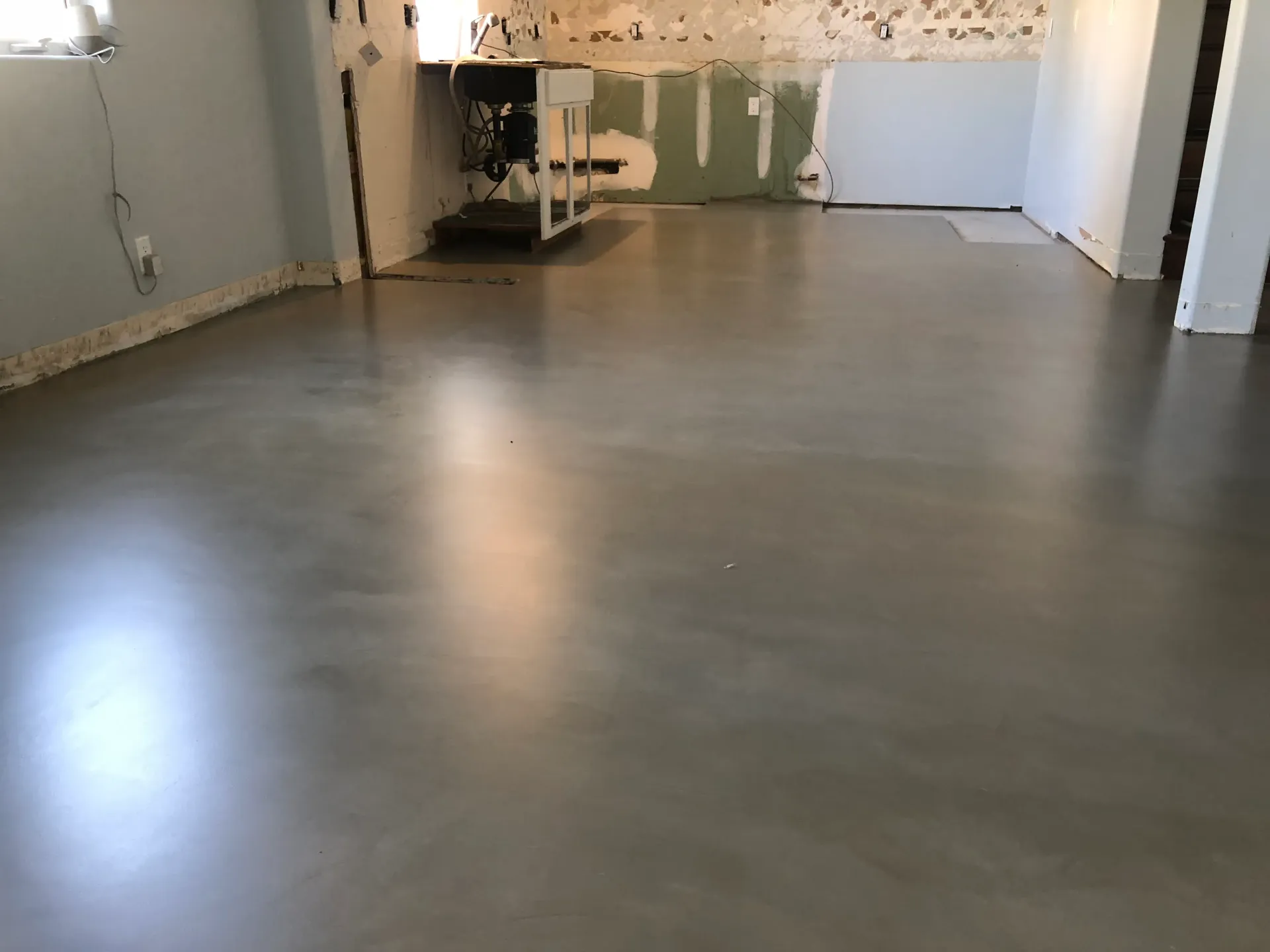 A room with a concrete floor and a white wall.