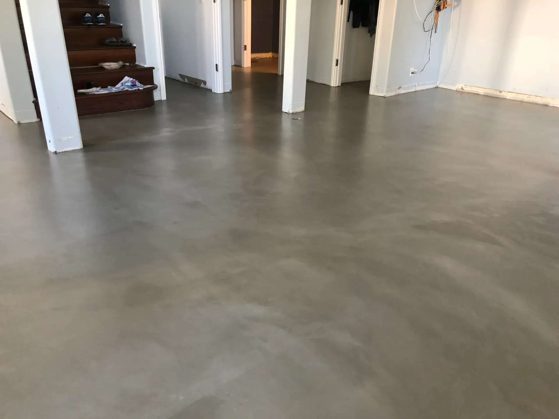 A room with a concrete floor and stairs in the background.