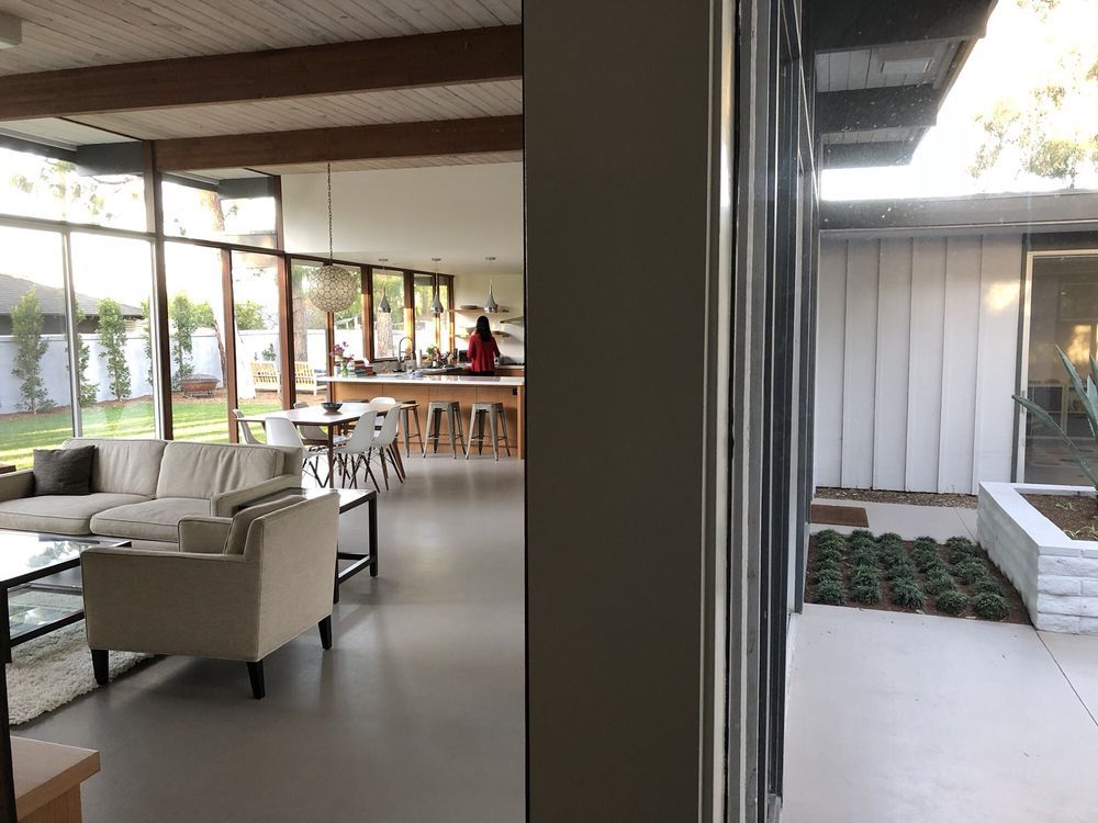 A living room with a couch and chairs and a kitchen in the background