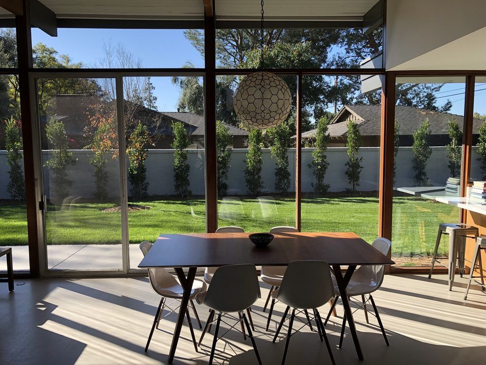 A dining room with a table and chairs and a view of a backyard.