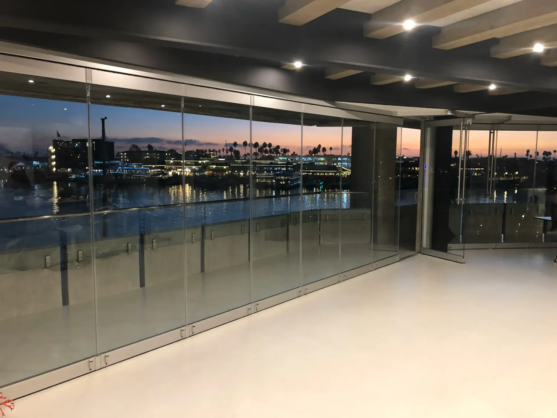 An empty room with a glass railing and a view of a body of water.