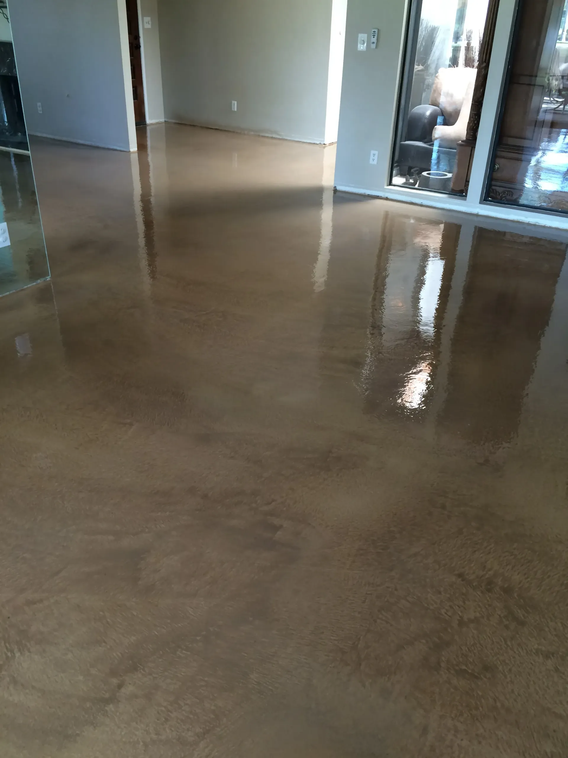 A living room with a shiny concrete floor and a sliding glass door.