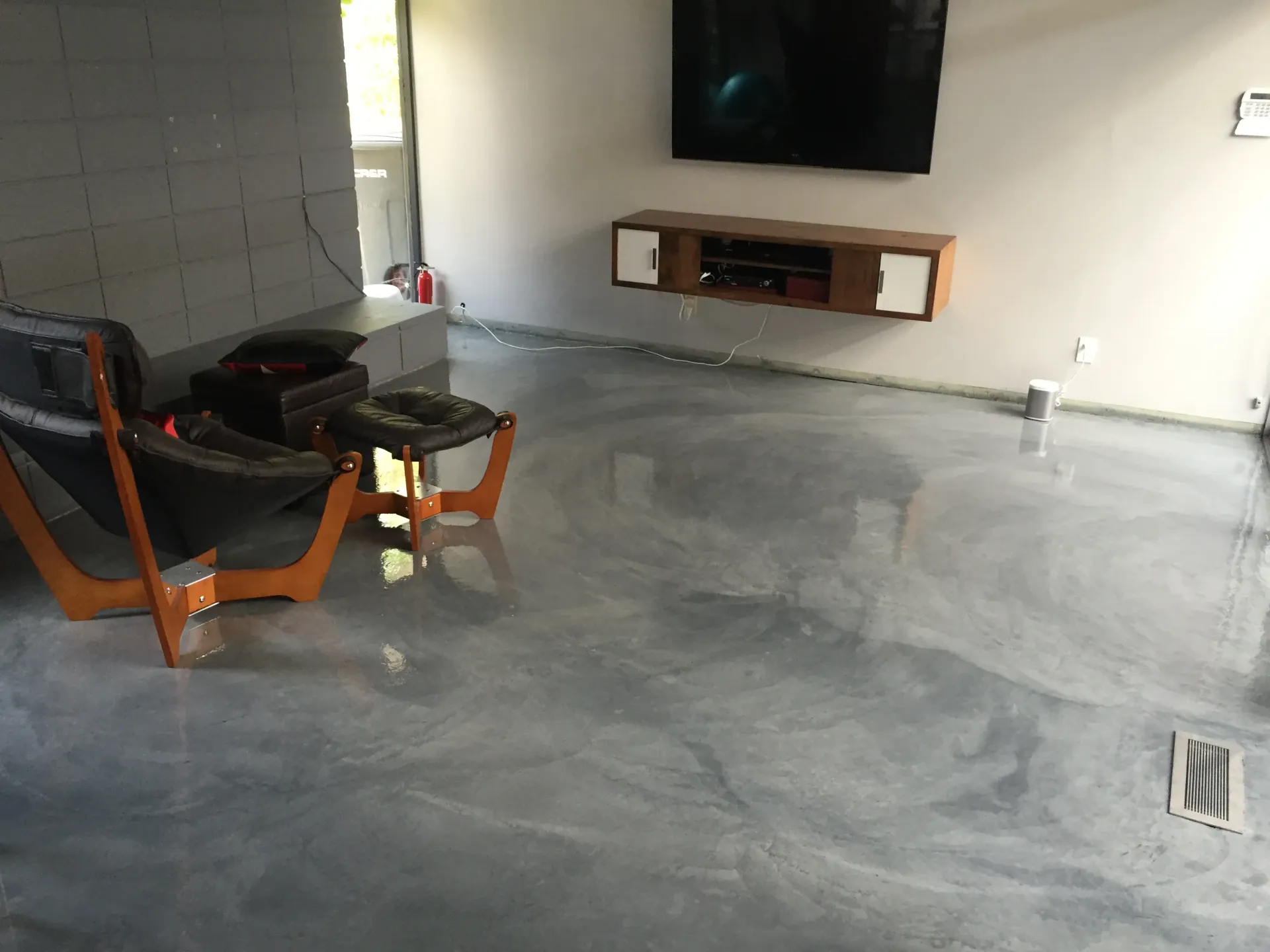 A living room with a concrete floor and a flat screen tv.