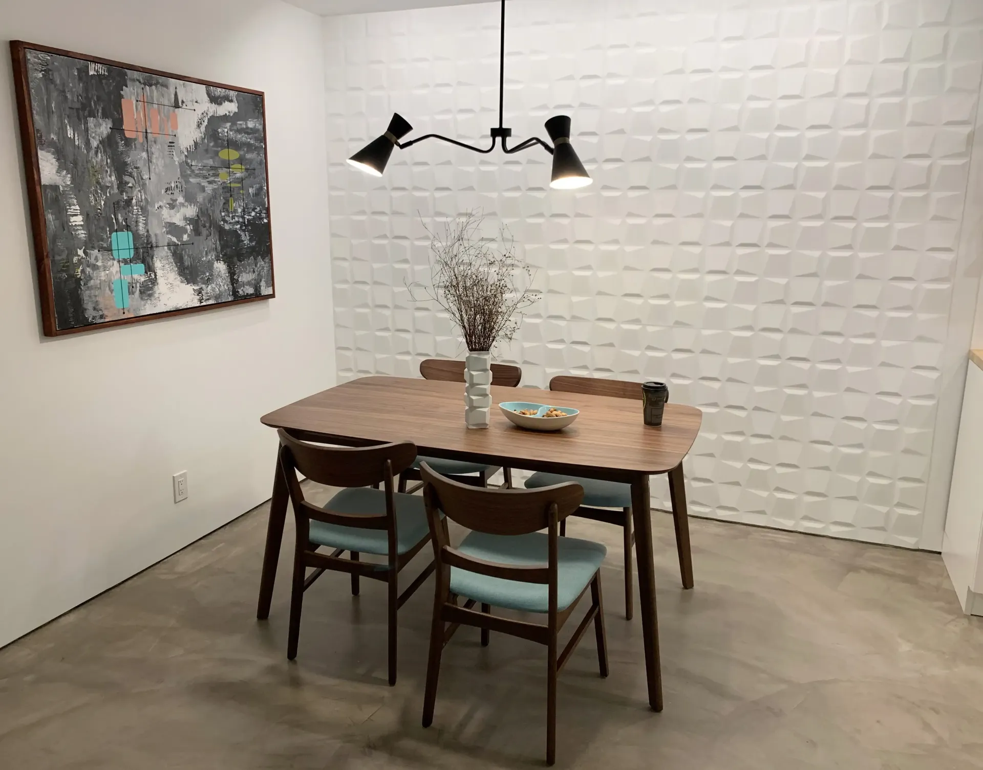 A dining room with a table and chairs and a painting on the wall.