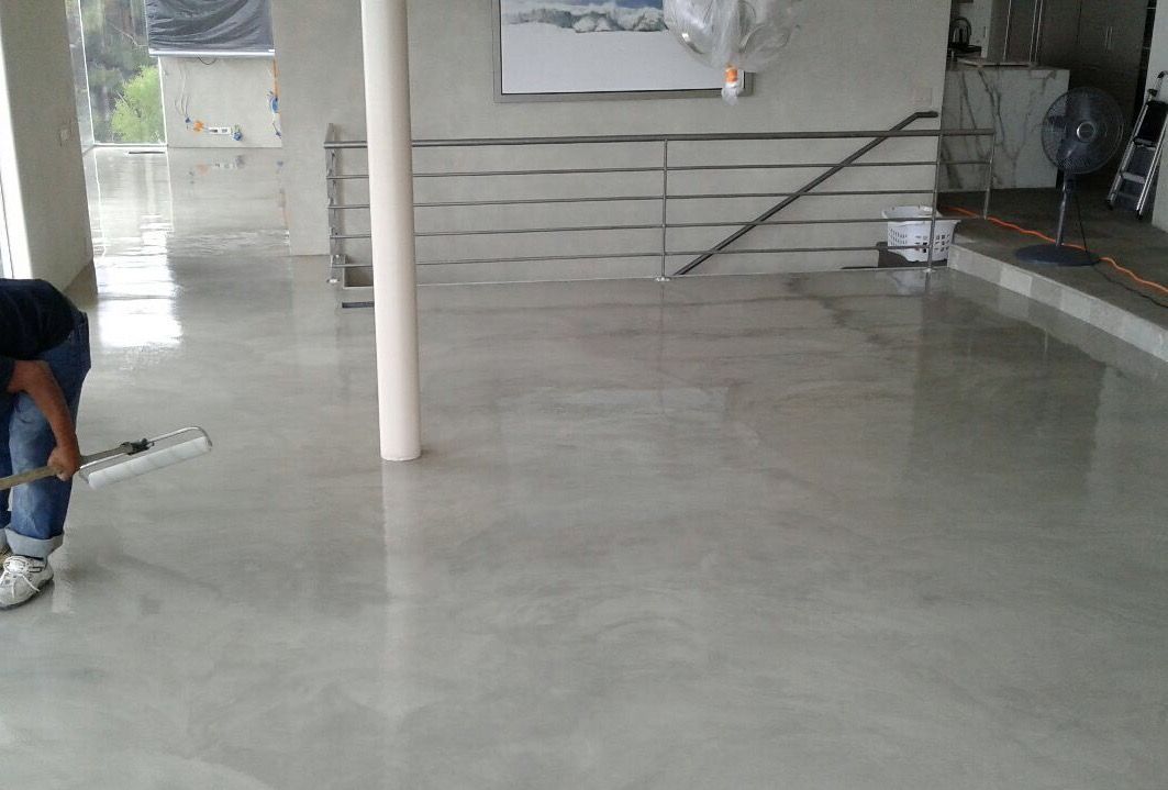 A man is cleaning a concrete floor with a broom.