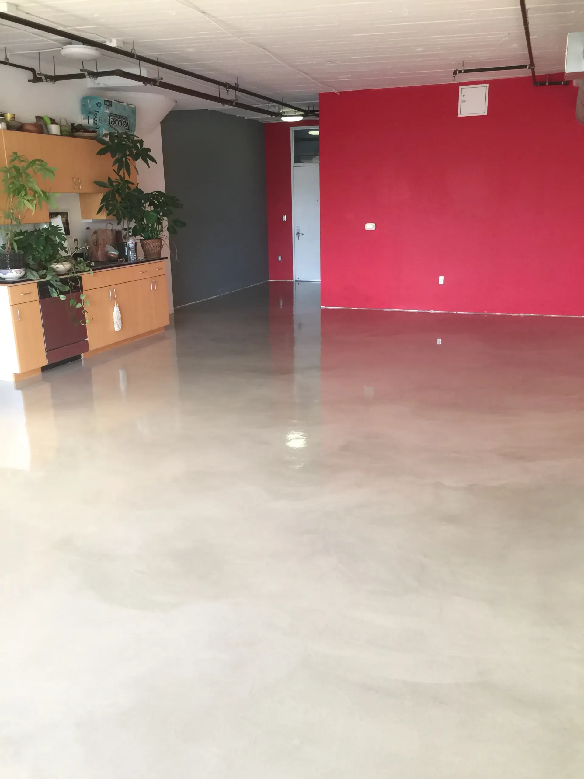 An empty room with a red wall and a white floor