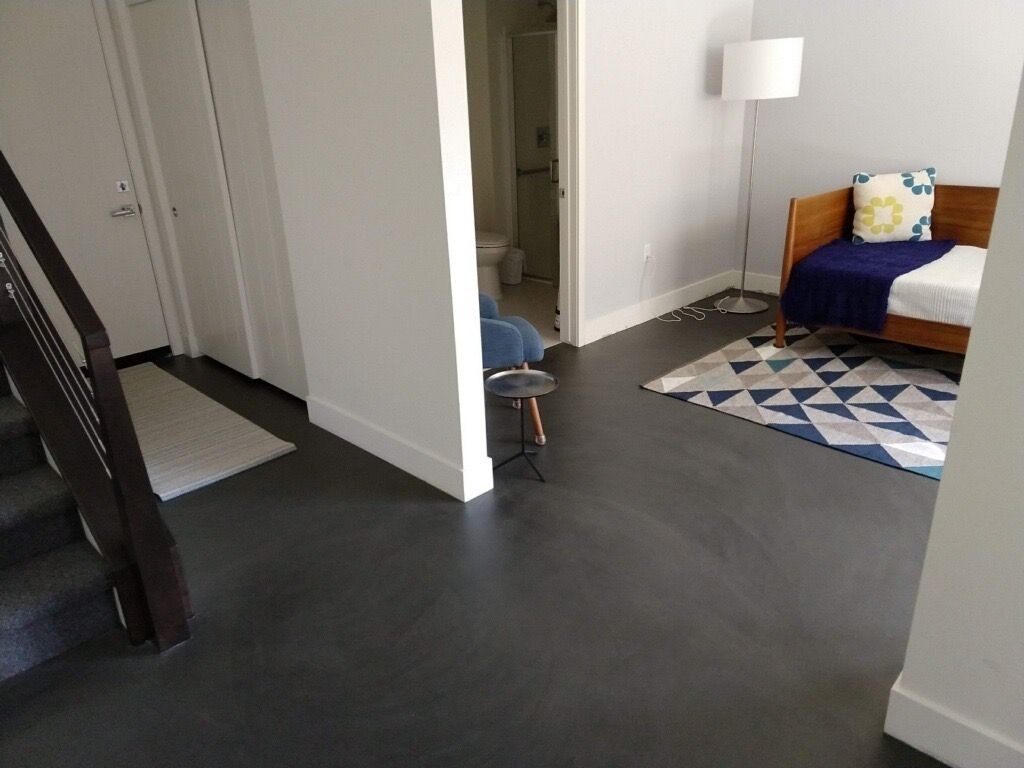 A living room with a couch , rug , lamp and stairs.