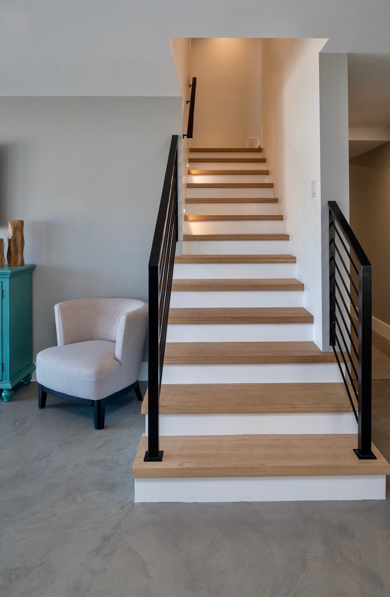 A staircase with wooden steps and a black railing in a living room