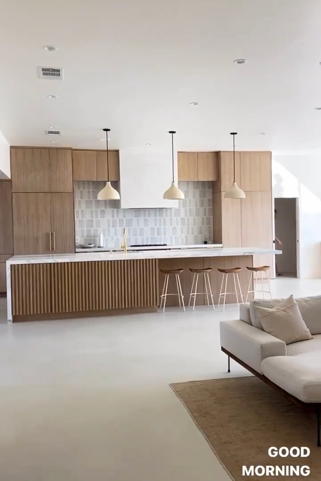 A living room with a couch and a kitchen with wooden cabinets