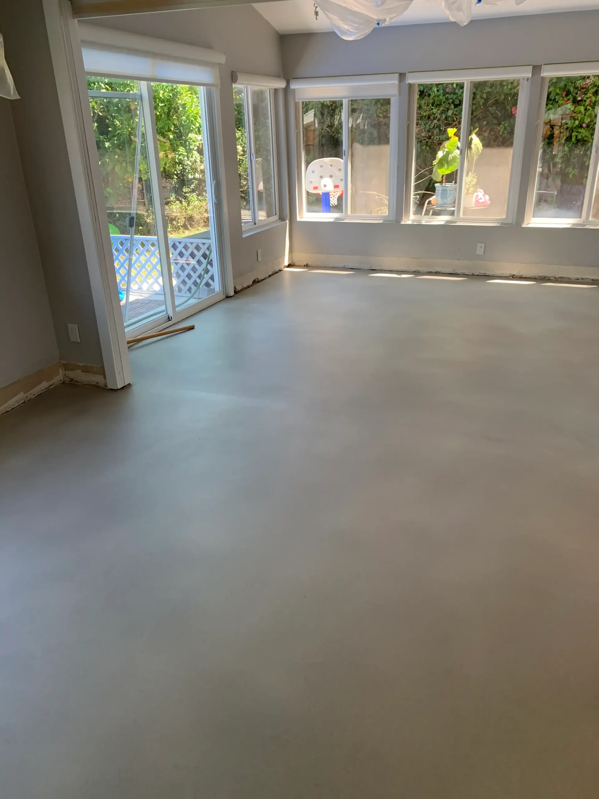 A large empty room with lots of windows and a concrete floor.