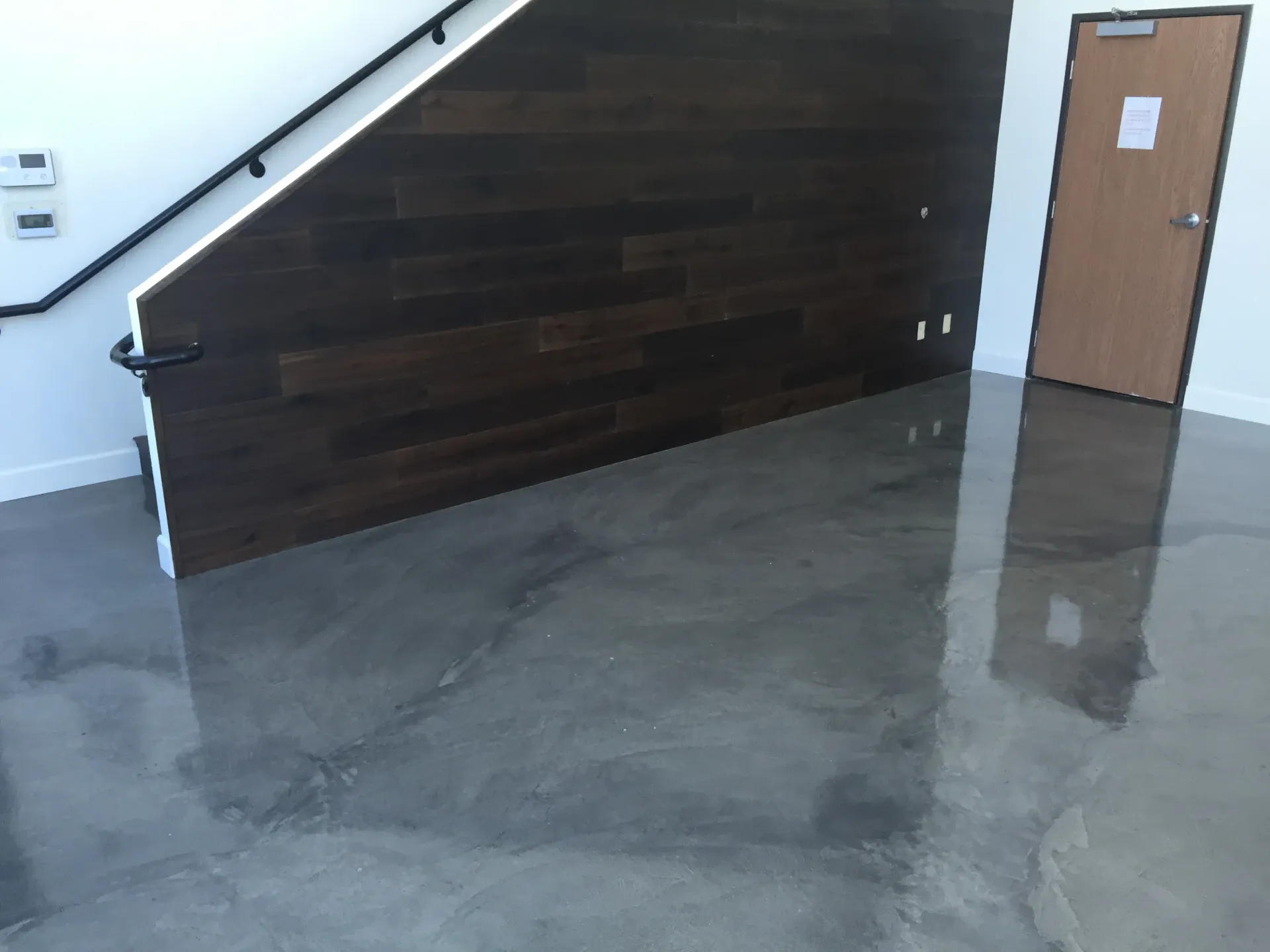 A staircase with a wooden wall and a shiny concrete floor