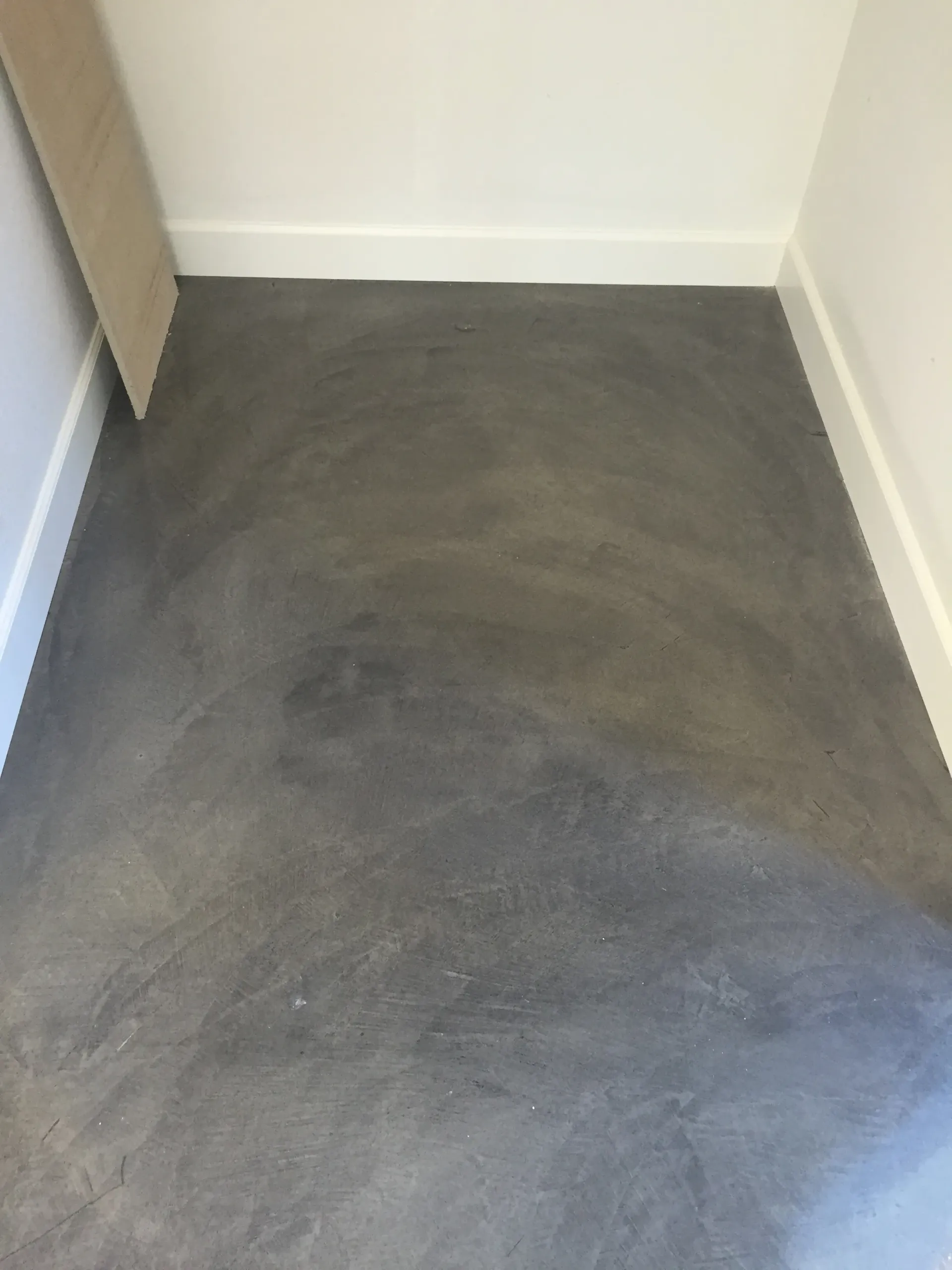 A gray carpeted floor in a room with a white wall.