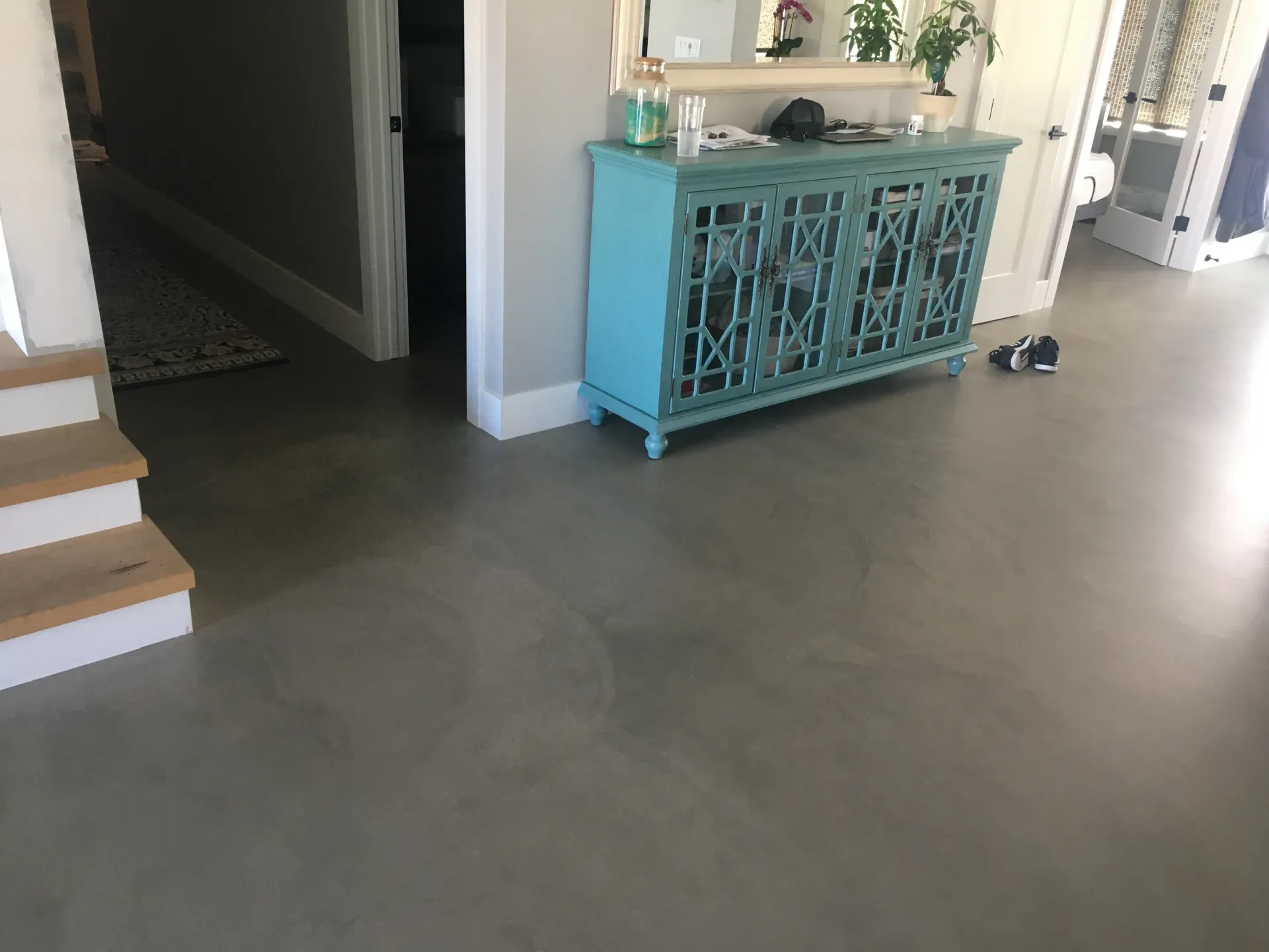 A blue cabinet is sitting on a concrete floor in a hallway next to stairs.
