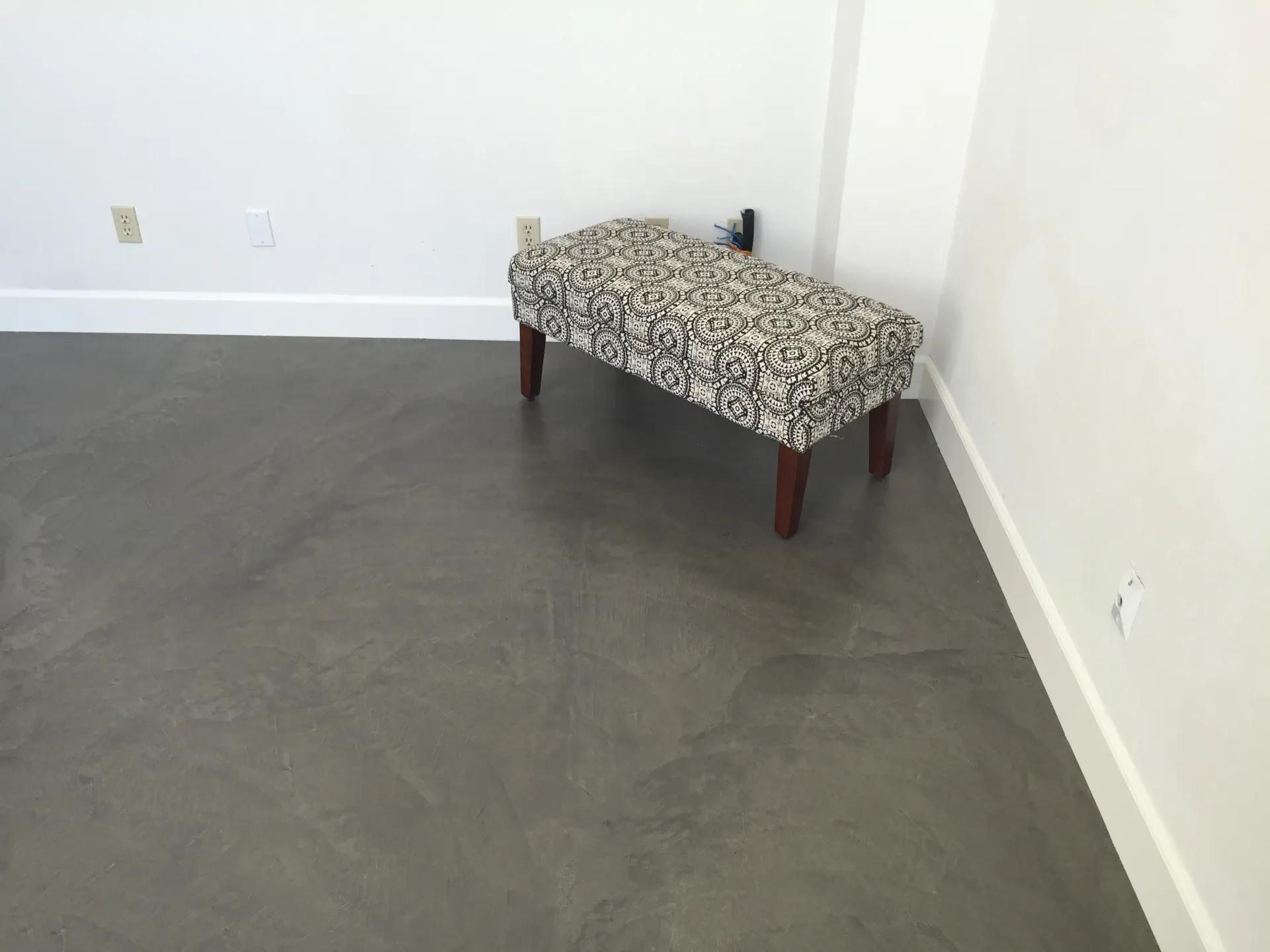 A black and white ottoman sits on a concrete floor in a room