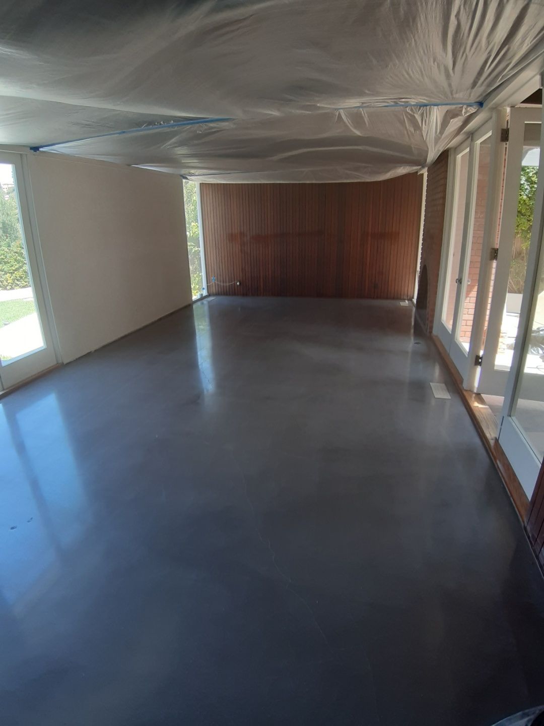 A large empty room with a concrete floor and a lot of windows.