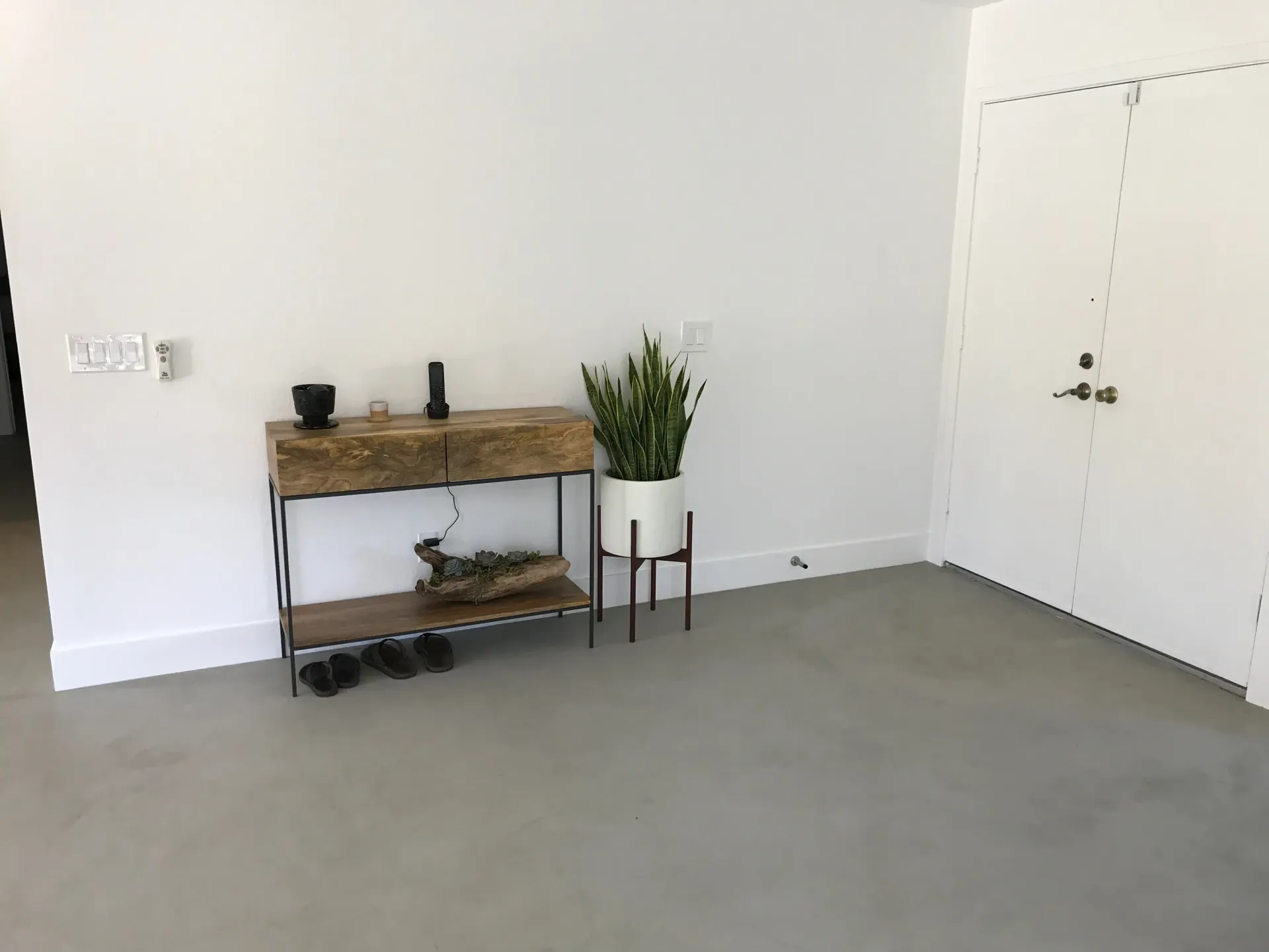 A room with a table and a potted plant on the floor.