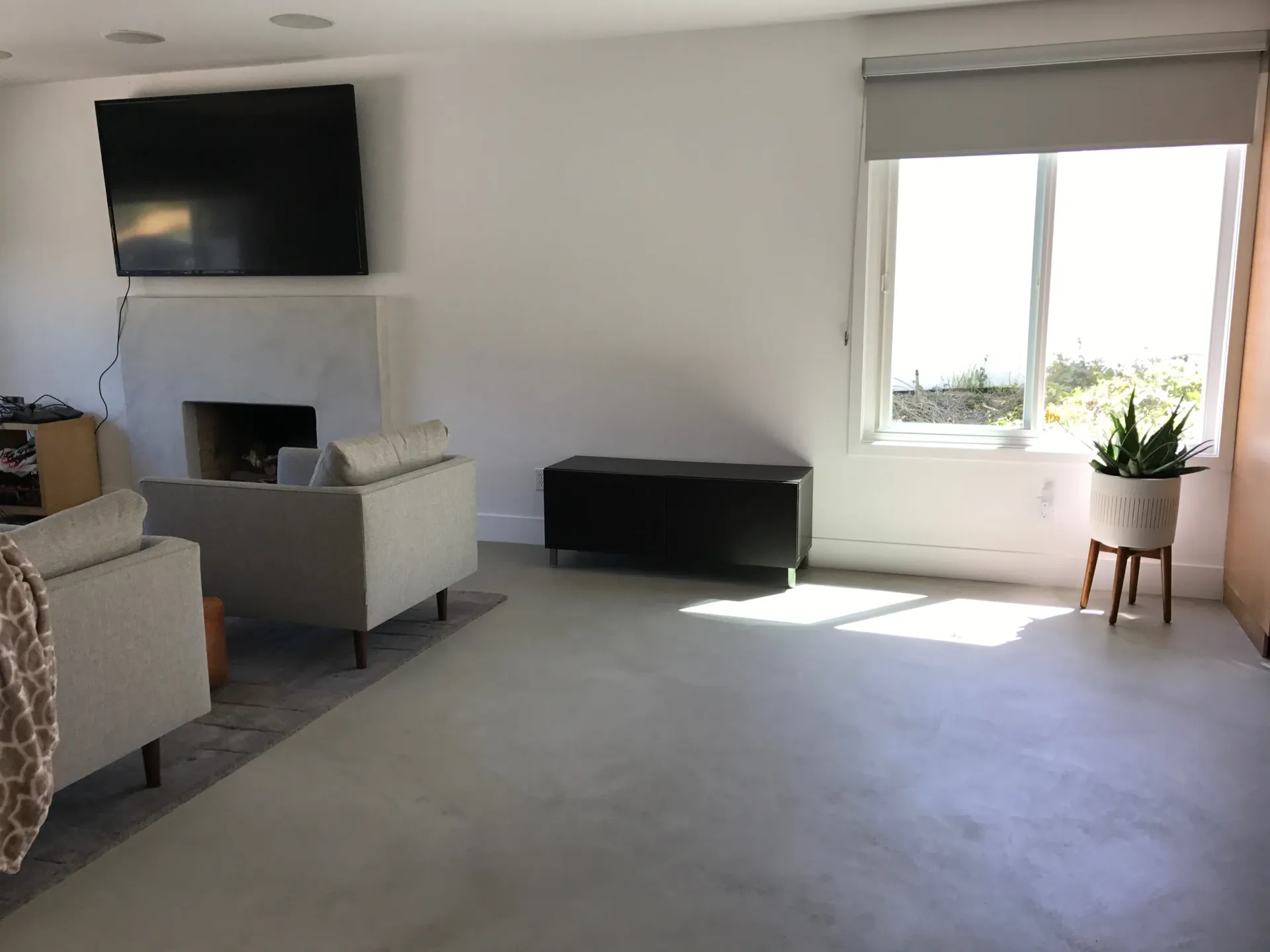 A living room with a fireplace , chairs , and a flat screen tv.