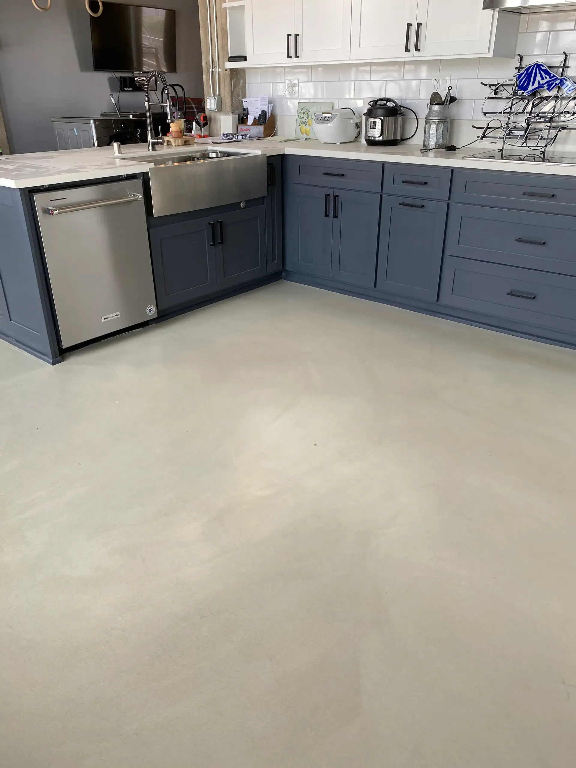 A kitchen with blue cabinets , white counter tops , and a stainless steel dishwasher.