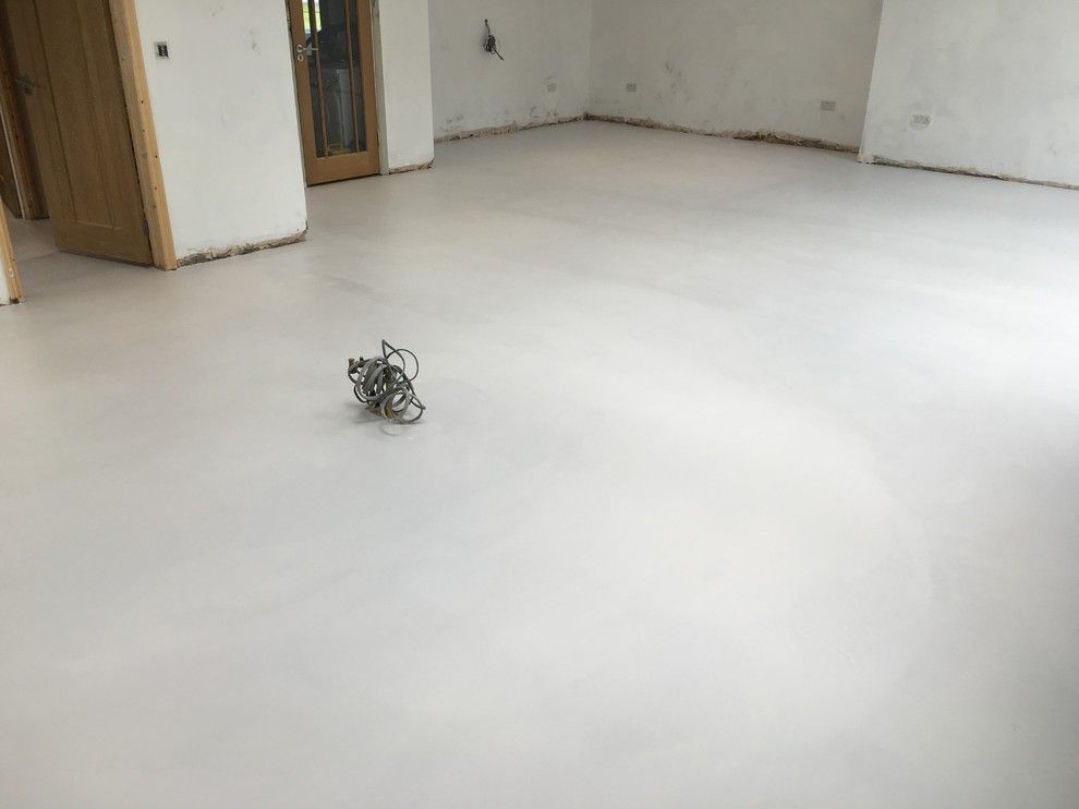 A robot is sitting on a white floor in a room.