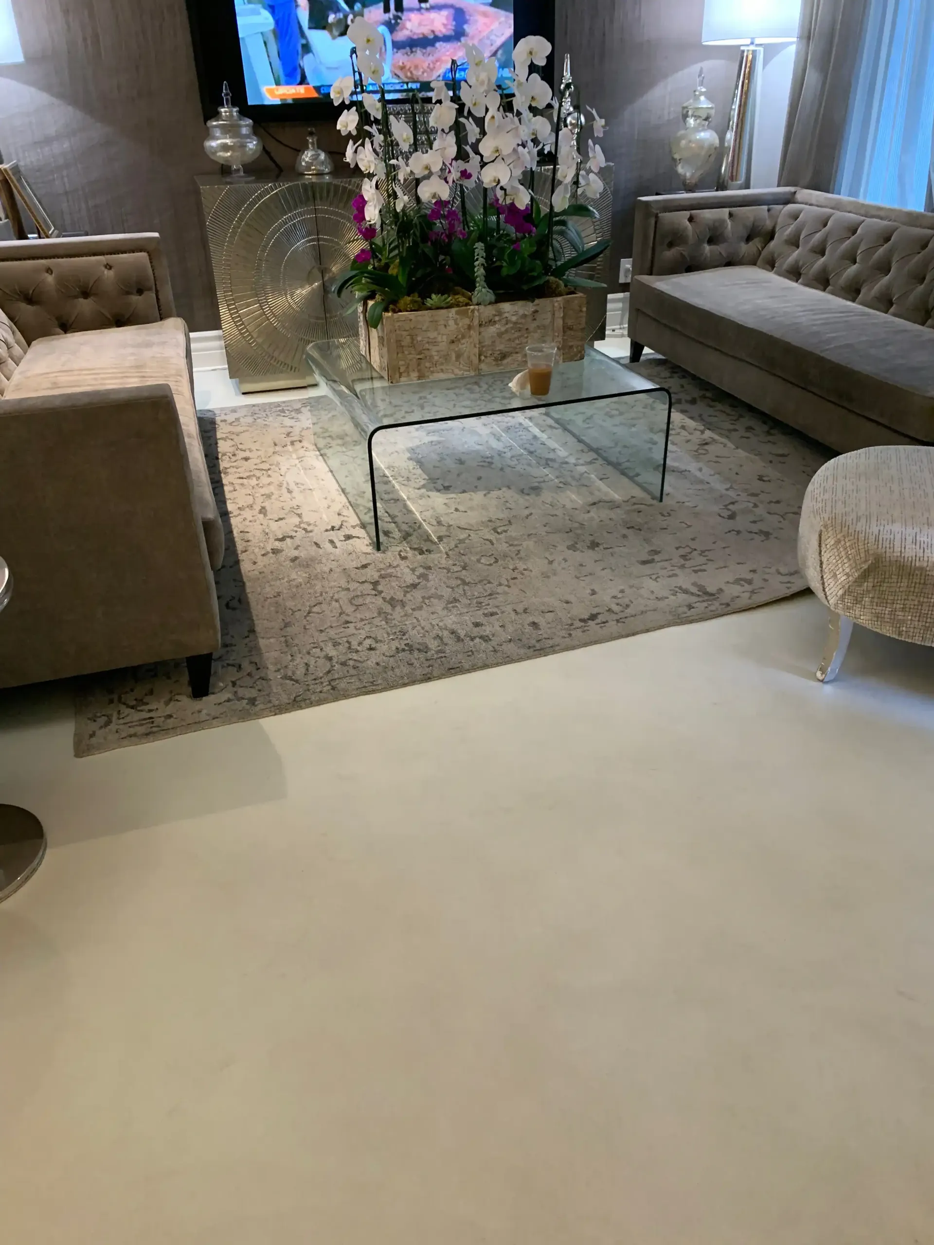 A living room with a couch , ottoman , coffee table and television.